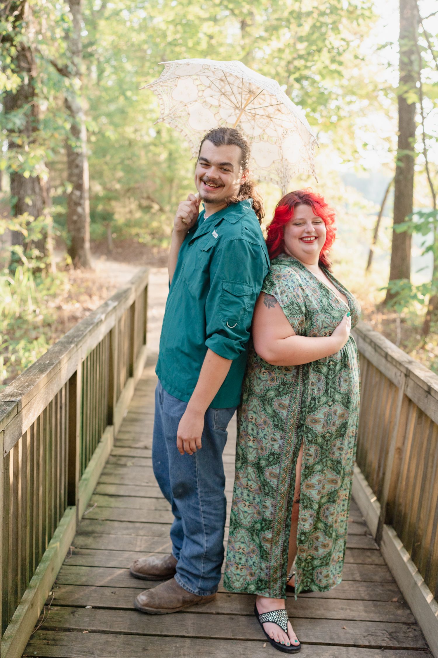 A romantic photoshoot on a wooden walkway with trees and natural lighting in the background.