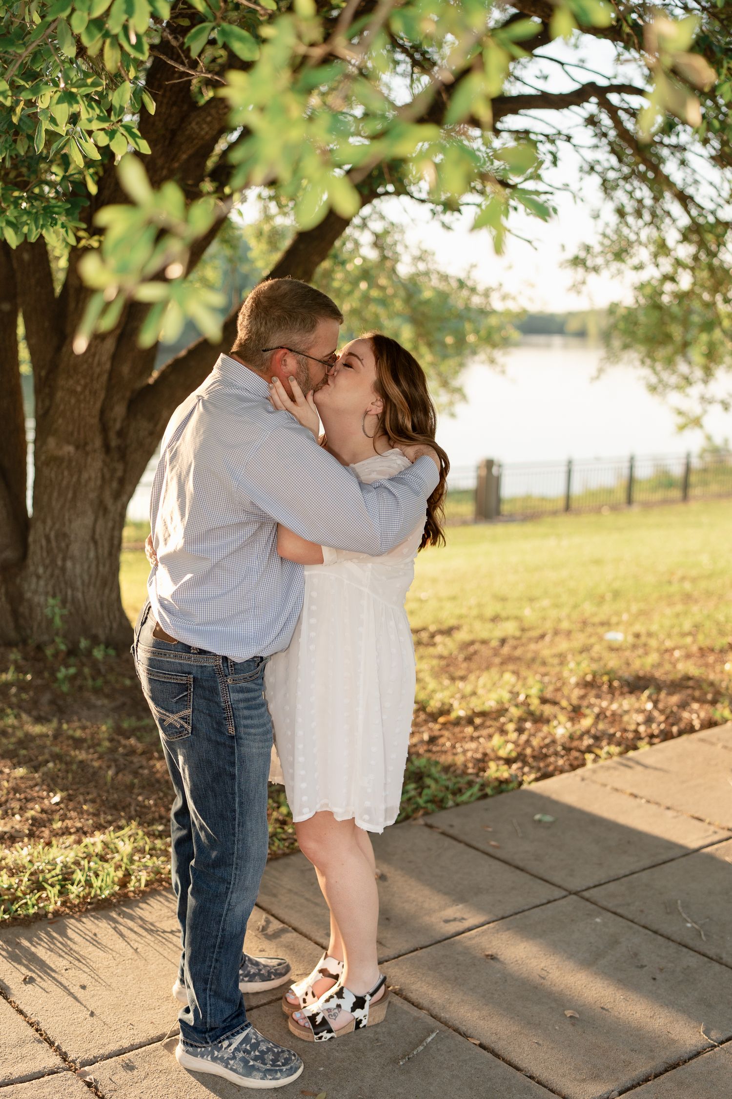A passionate kiss shared between a couple under a tree during golden hour.