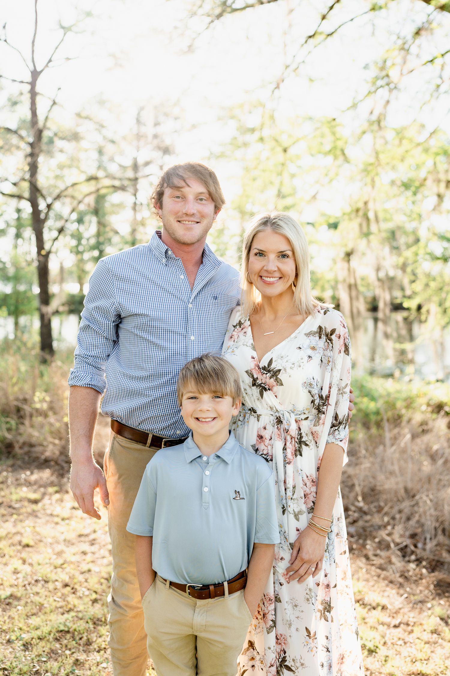 Family poses together in coordinated blue and floral outfits during outdoor photo session.
