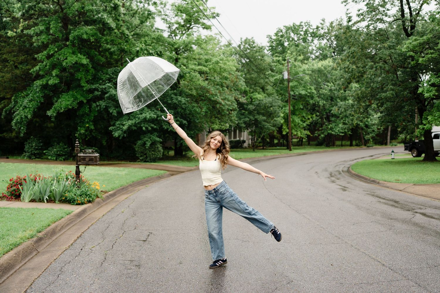 Dancing with an umbrella on a winding path surrounded by lush green trees.