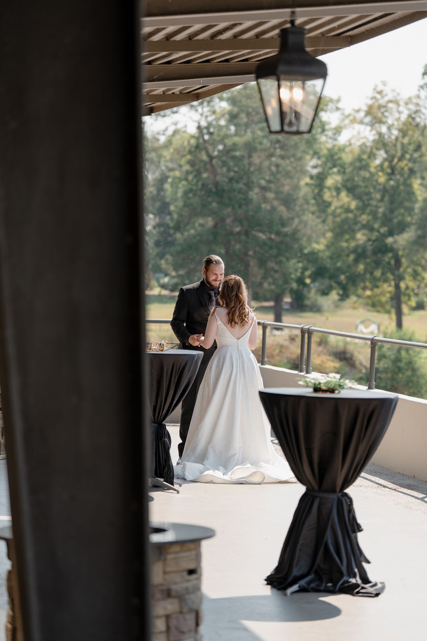 Outdoor wedding venue terrace with black cocktail tables and scenic nature views.