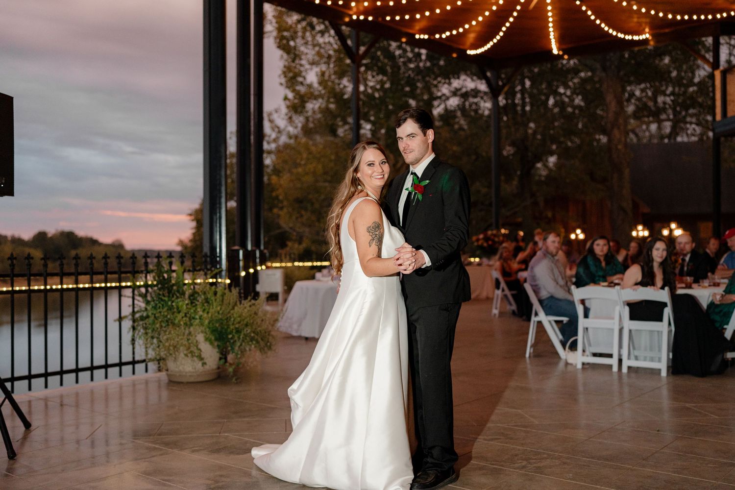 Evening wedding reception with string lights creating romantic ambiance on outdoor patio.