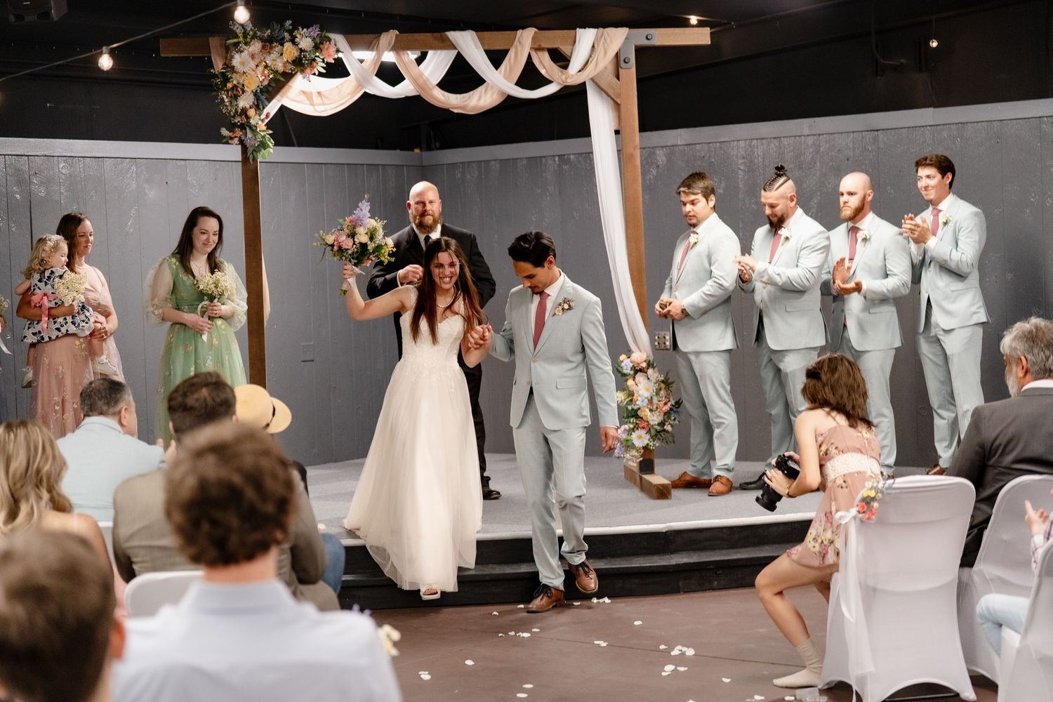 A wedding party celebrates with dancing and joyful moments during a reception in a decorated venue.