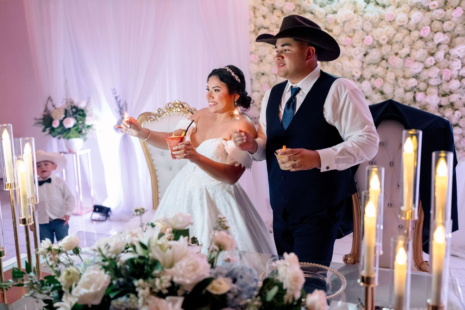Wedding reception venue decorated with white floral wall arrangements and soft pink lighting.