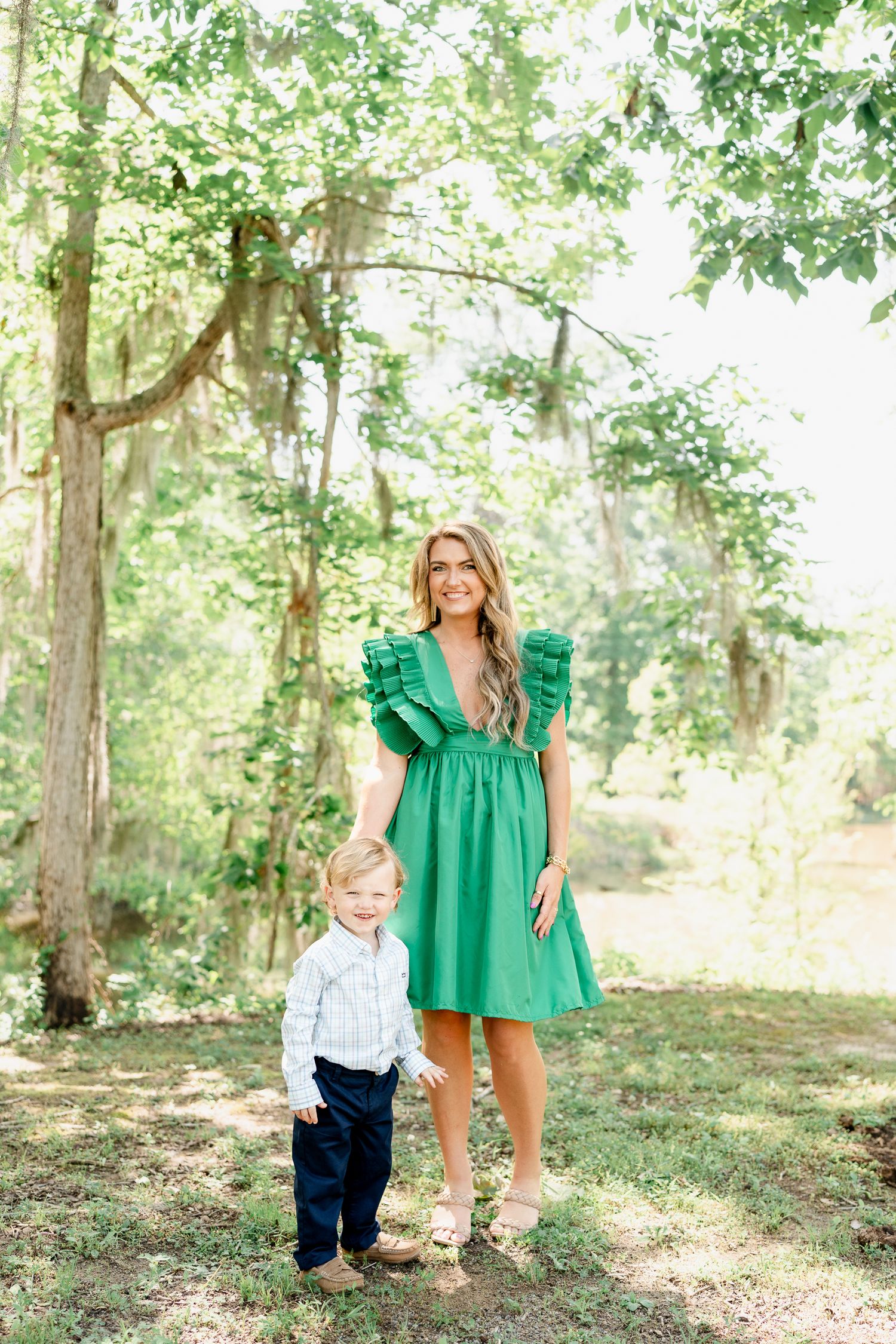 Parent and child interacting playfully in a sun-dappled forest setting.
