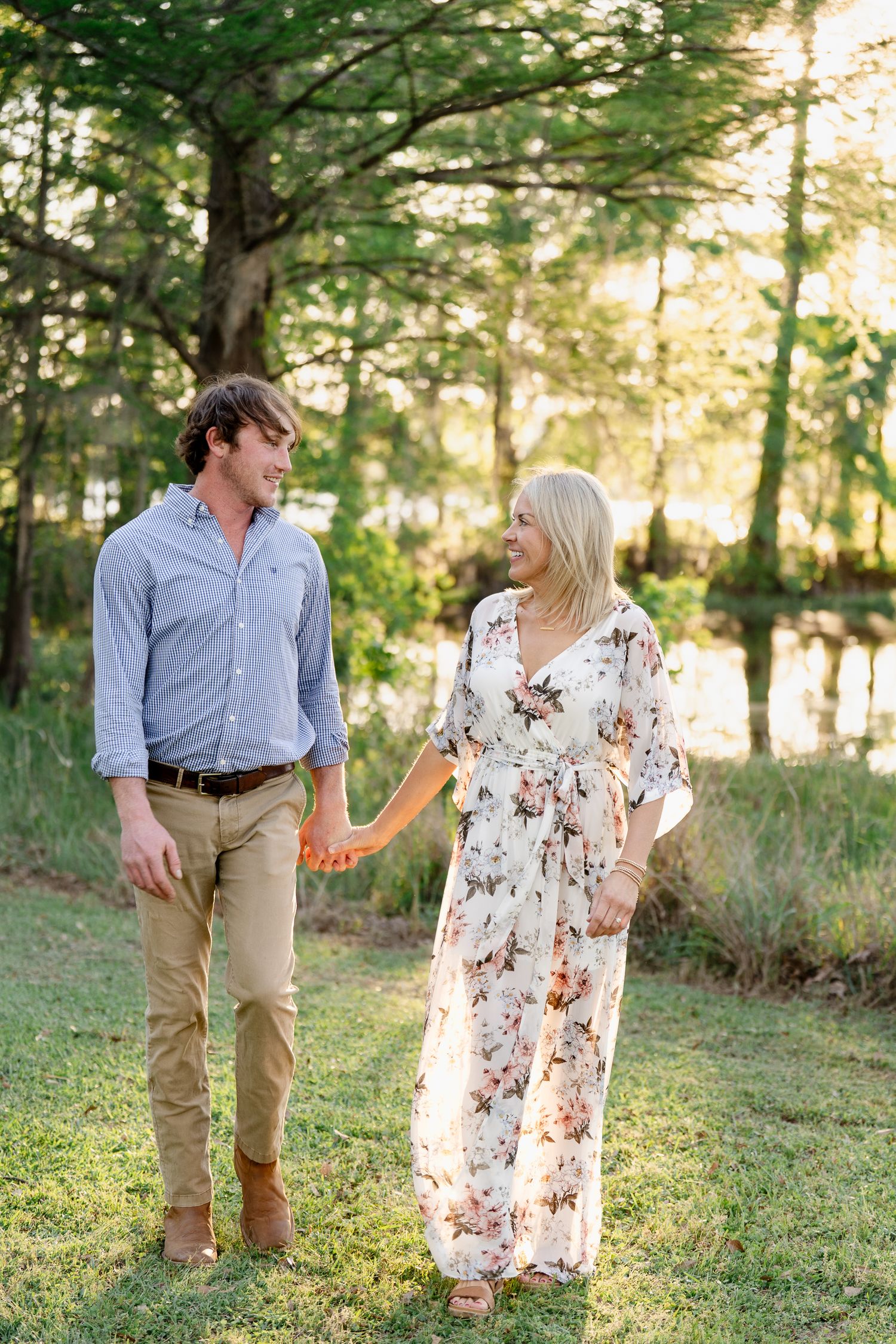 A couple holding hands while walking through a scenic wooded area.