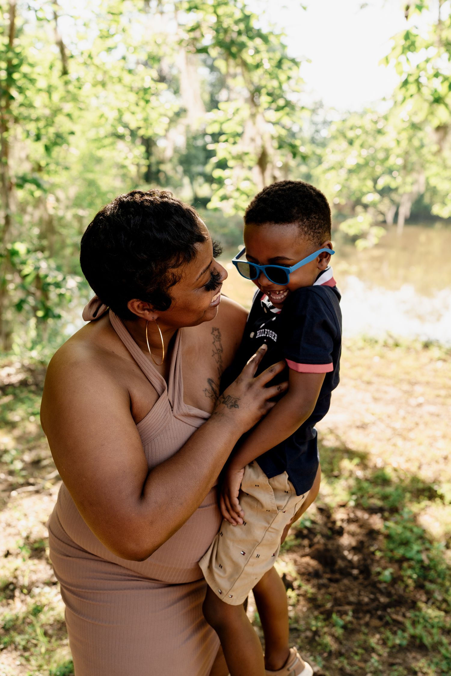 Heartwarming moment between parent and child wearing sunglasses in a natural forest setting.