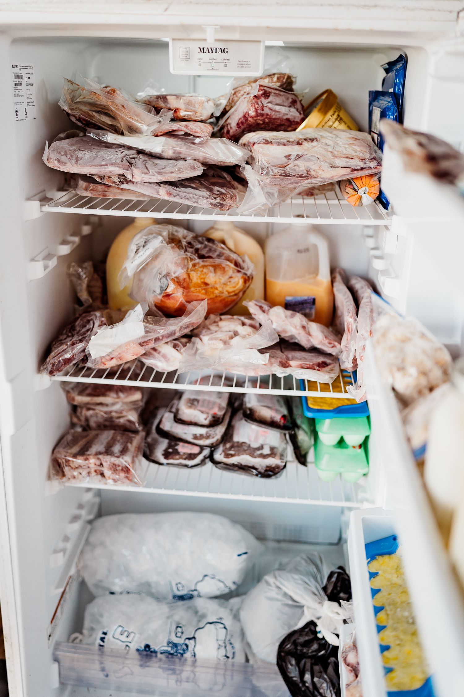 A freezer filled with frozen meat packages and food items on multiple shelves.