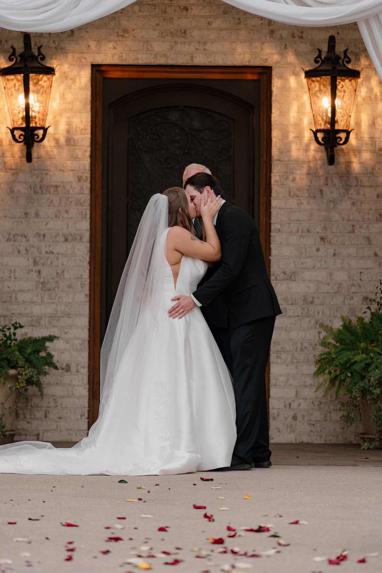 Series of romantic first look moments between newlyweds against brick wall with rose petals.