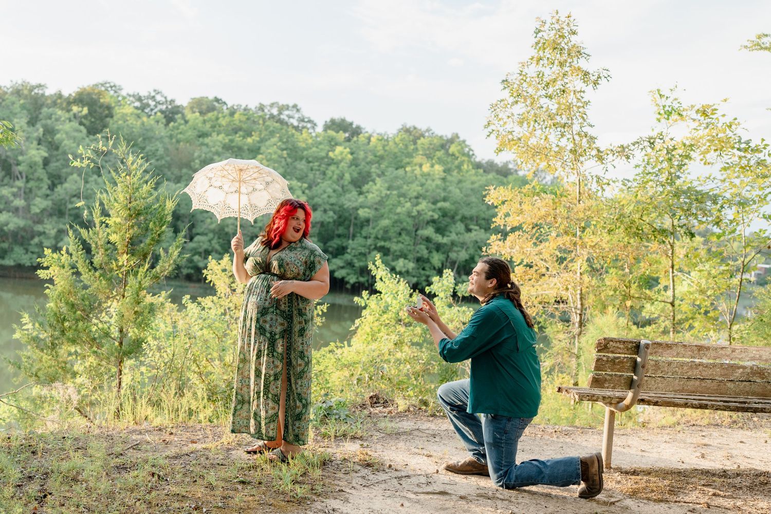 Two people propose marriage on a scenic overlook with fall foliage and mountains in the background.