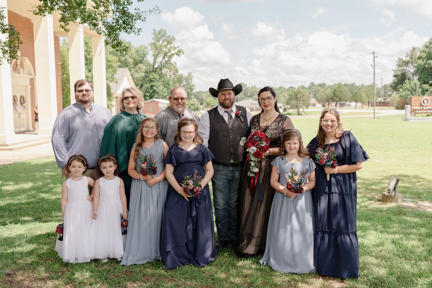 Large wedding party group photo outdoors with coordinated blue and gray attire.