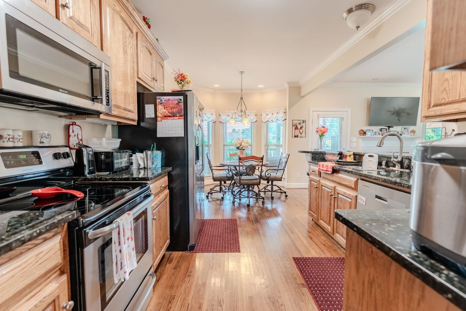 Modern kitchen with honey oak cabinets and stainless steel appliances extending into a bright dining area.
