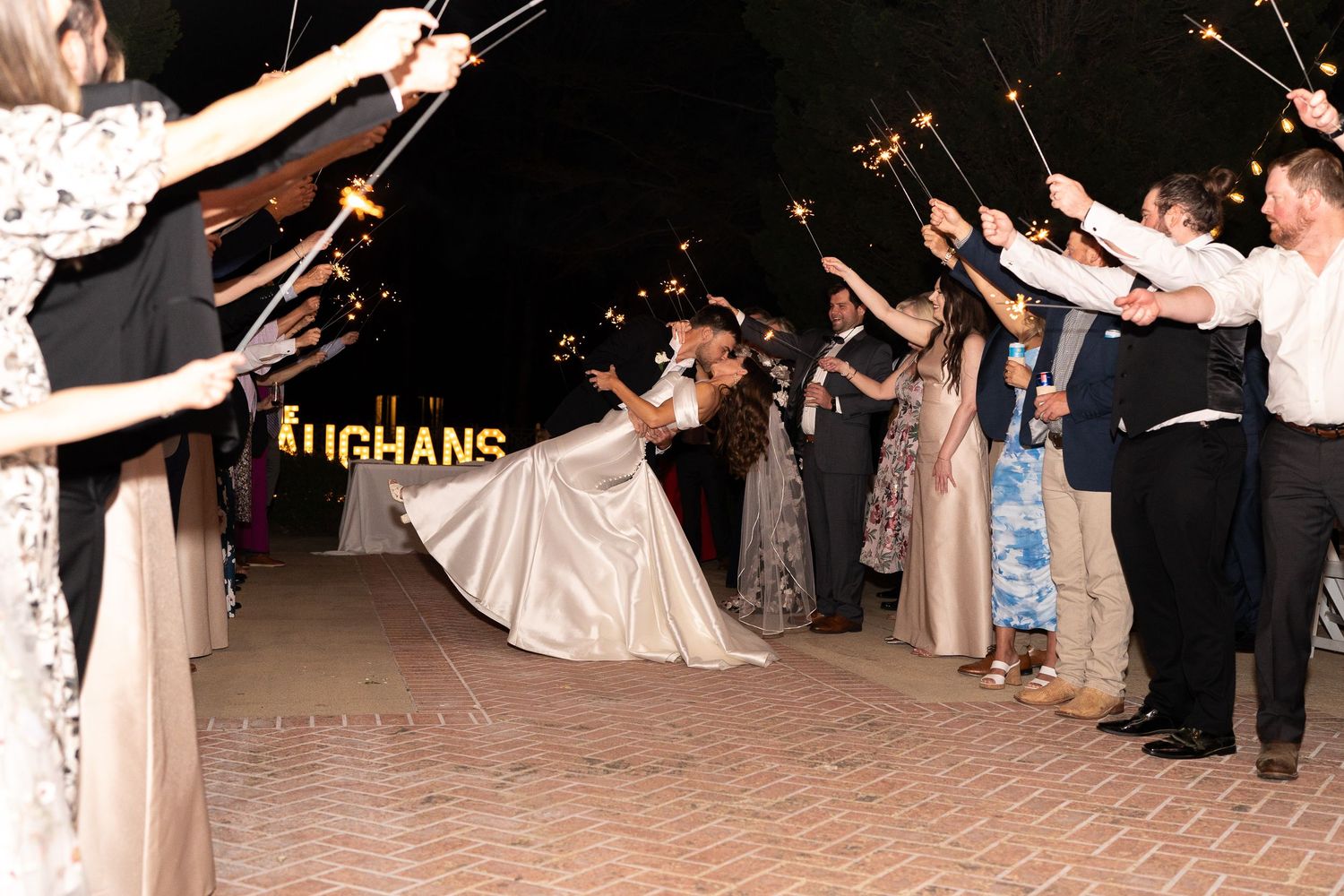 Wedding guests hold sparklers creating a magical tunnel exit for the newlyweds.