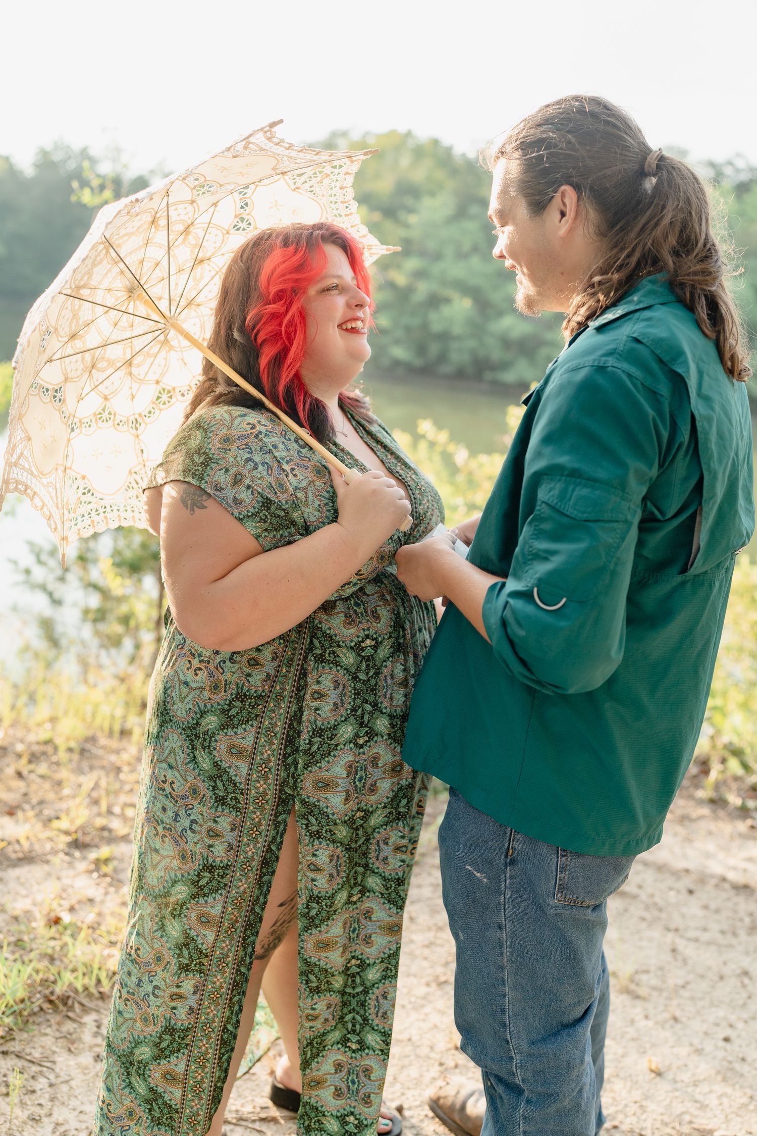 Two people in casual attire share an intimate moment while holding a vintage lace umbrella outdoors.
