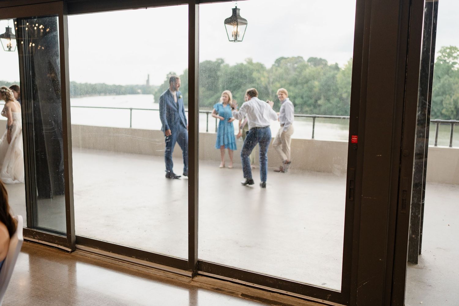 Panoramic view of multiple glass doors and windows in a modern building with people visible on a balcony.