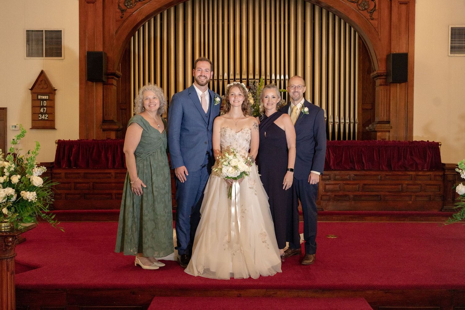 A group stands in front of a large pipe organ in a church sanctuary during a formal event.