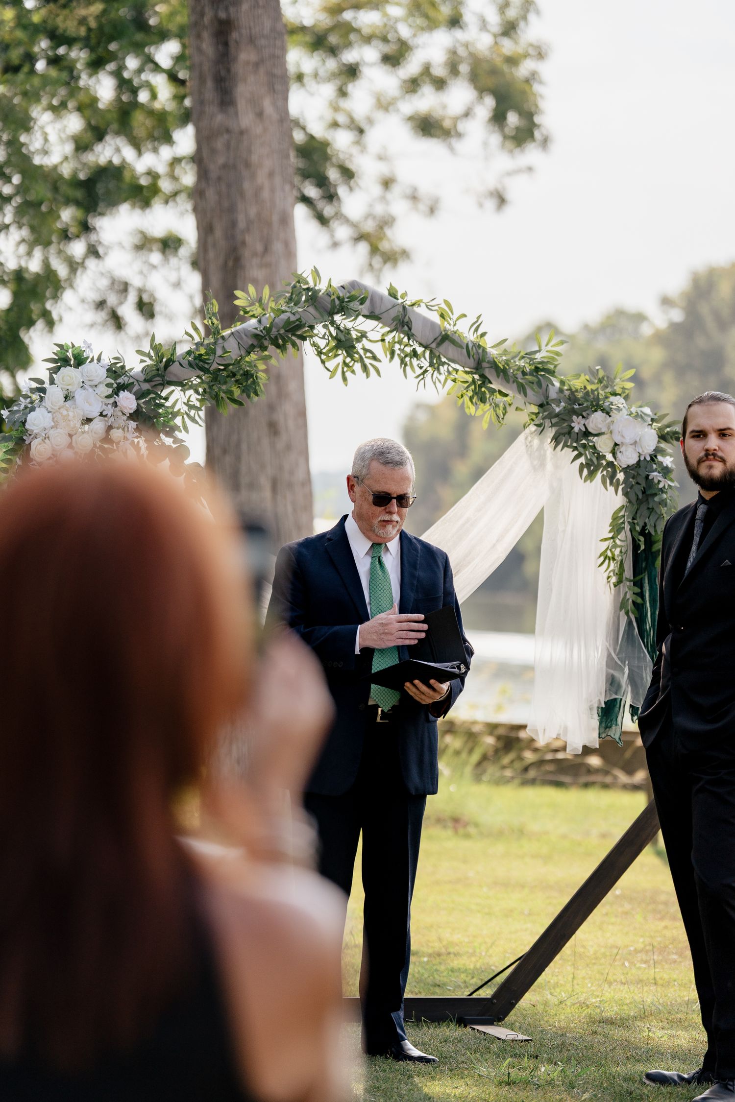 Wedding ceremony setup in a scenic outdoor location with white floral arch and natural decor.