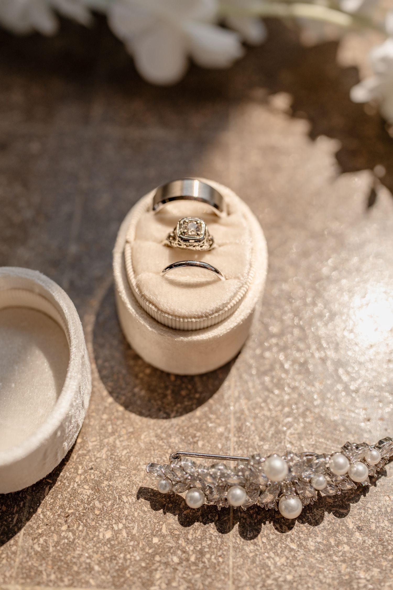 Wedding rings and jewelry arranged artistically on a sparkly surface.