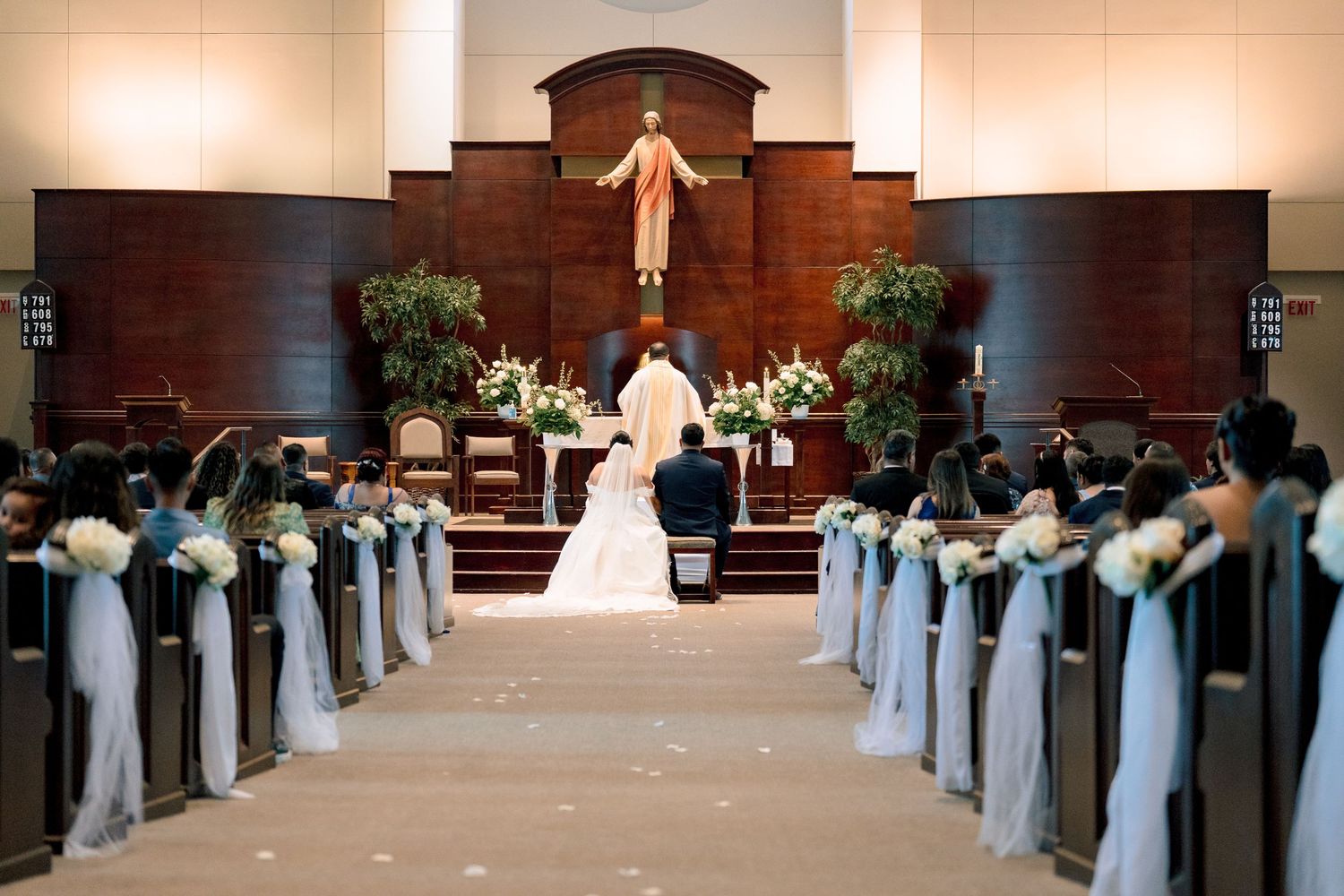 Church wedding ceremony setup with white and blue decorations along the aisle leading to a wooden altar.