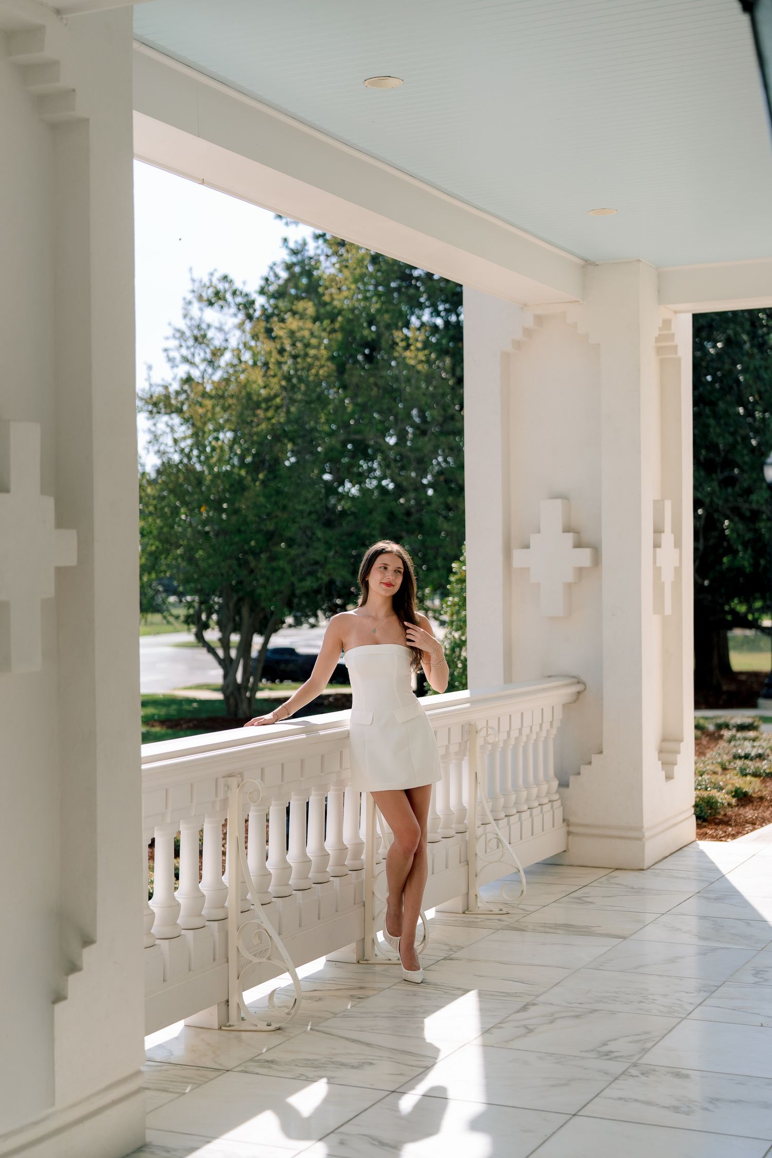 A bright white marble balcony with classical columns and balustrades extends along the exterior of an elegant building.