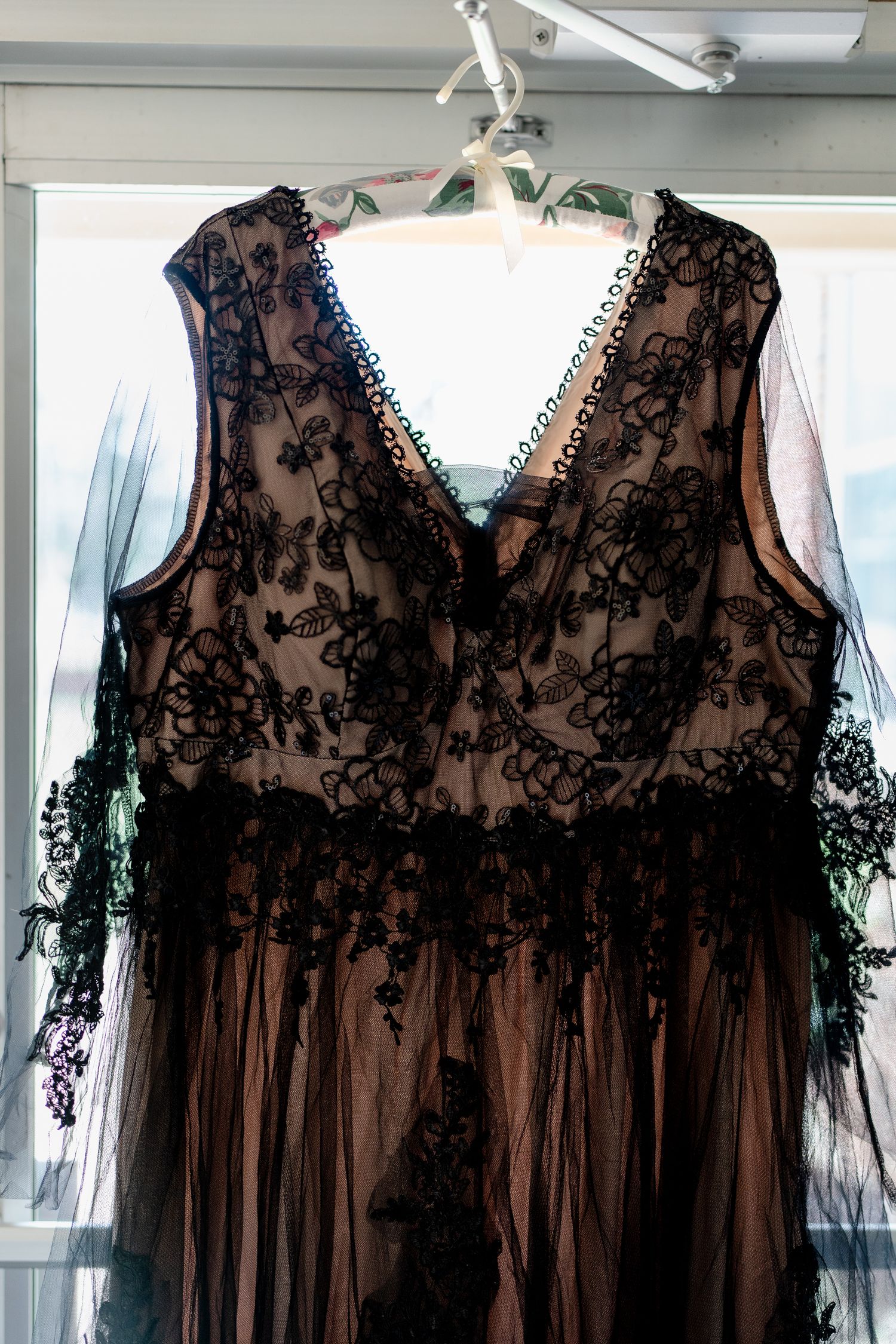 Elegant black lace bridesmaid dresses with sheer overlay hanging on display.