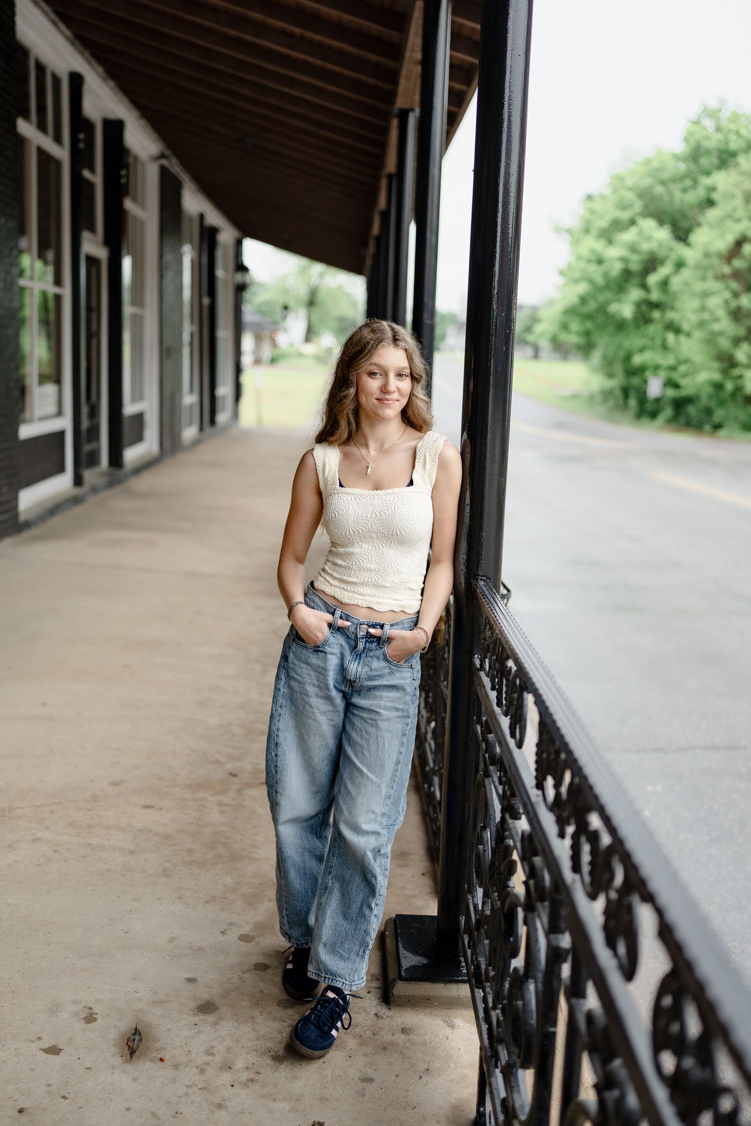 Fashion portrait series showing casual summer style with blue jeans and white top along a covered walkway.