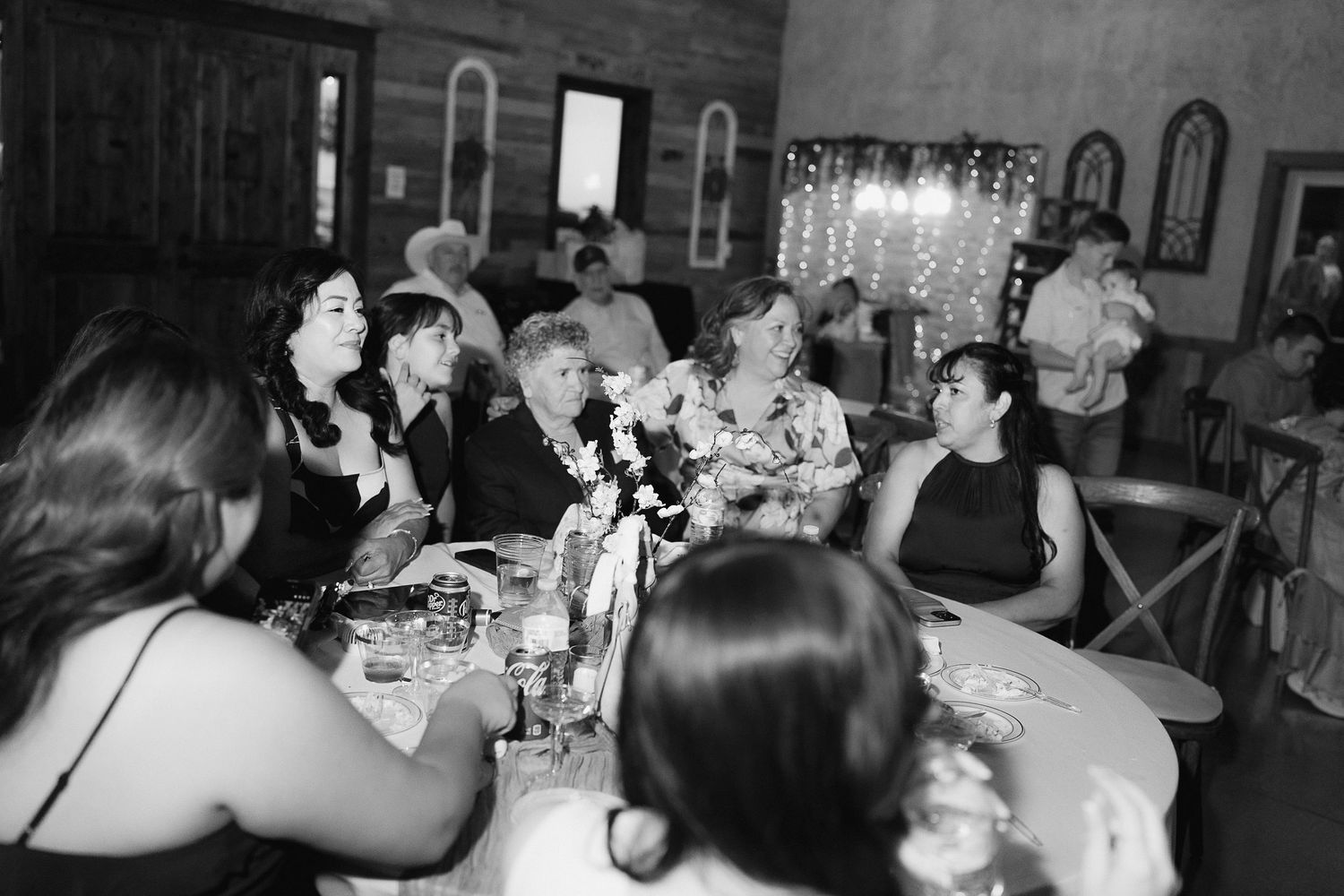 Wedding guests laughing and celebrating together at a candlelit reception table.