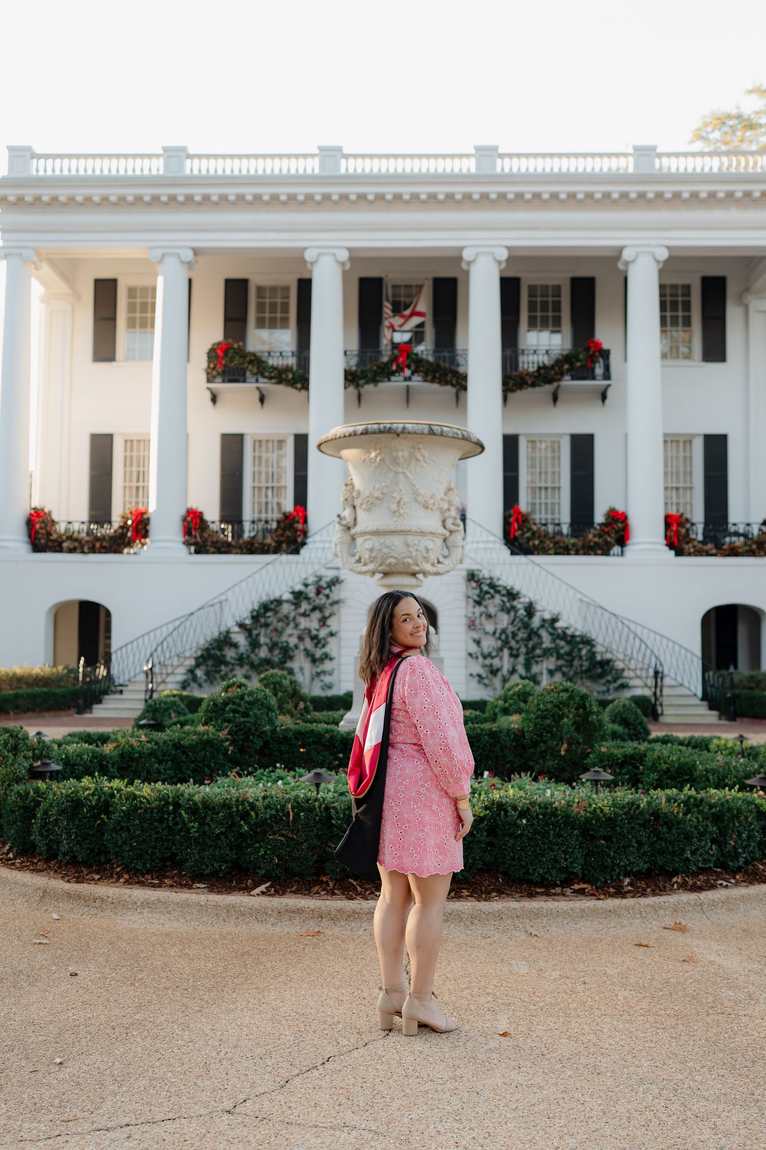 A photo series in front of a white colonial mansion with red flowers and columns on a sunny day.