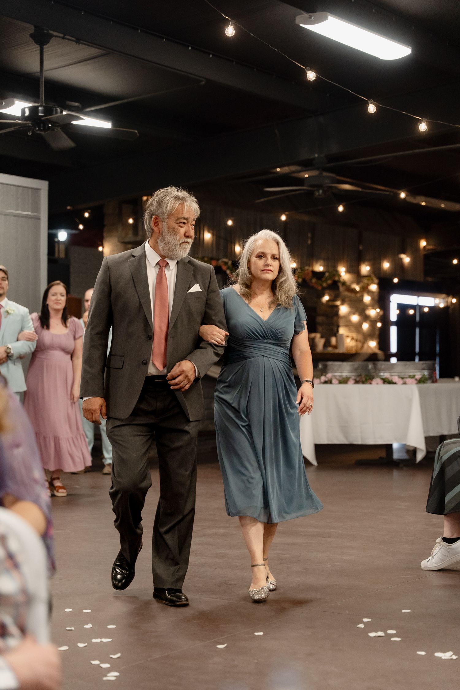 A wedding reception dance floor with couples dancing in formal attire and string lights overhead.