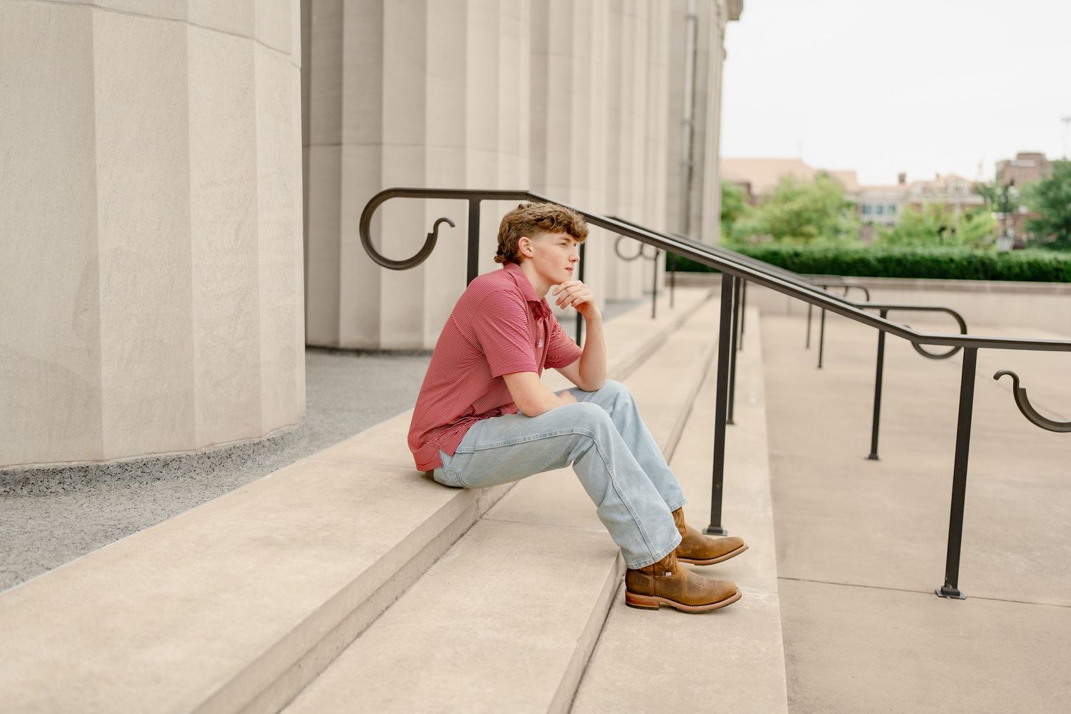 Relaxed posed shot sitting on concrete steps with decorative iron railing.