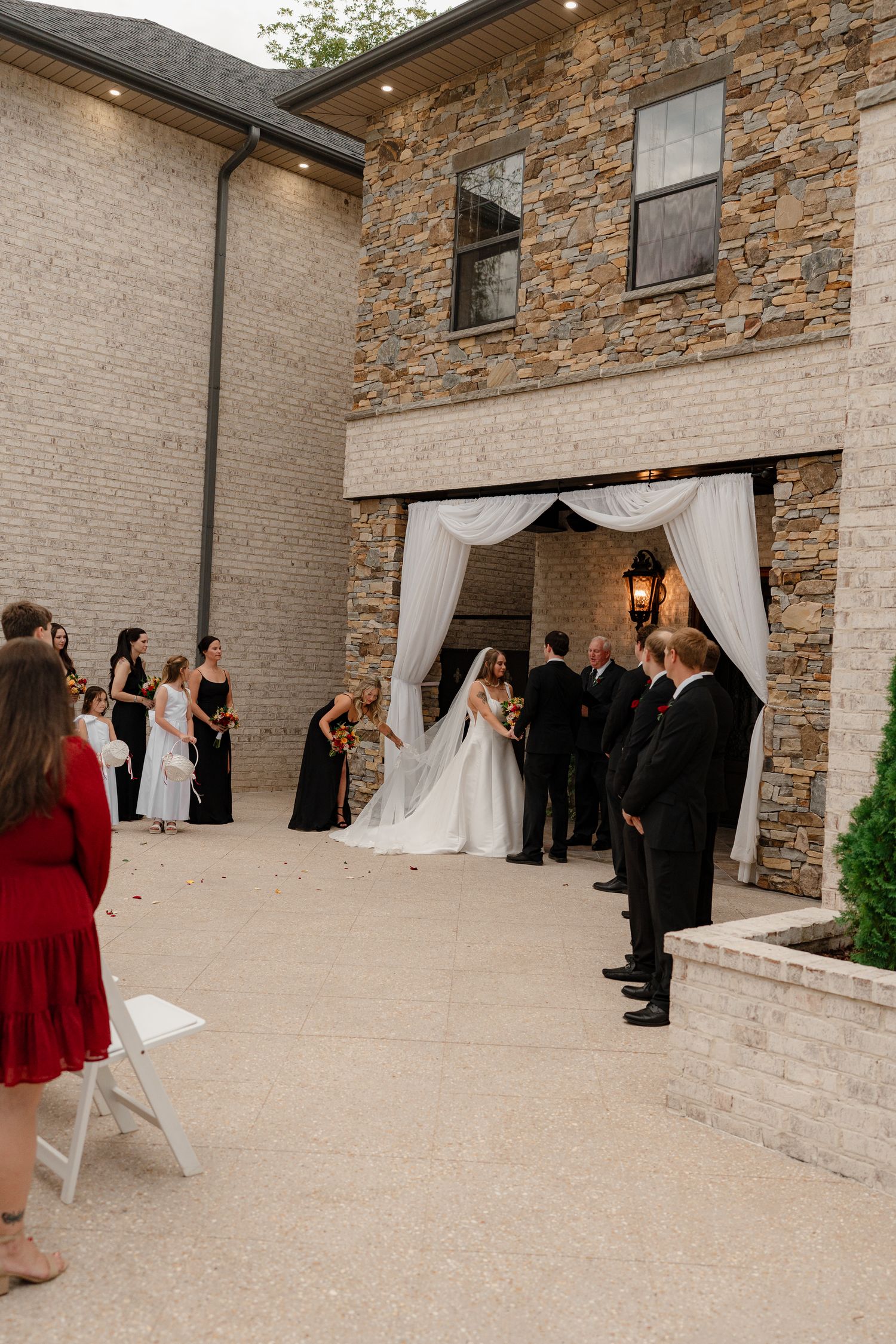 Wedding ceremony setup at an elegant stone venue with white drapes and chairs arranged for guests.
