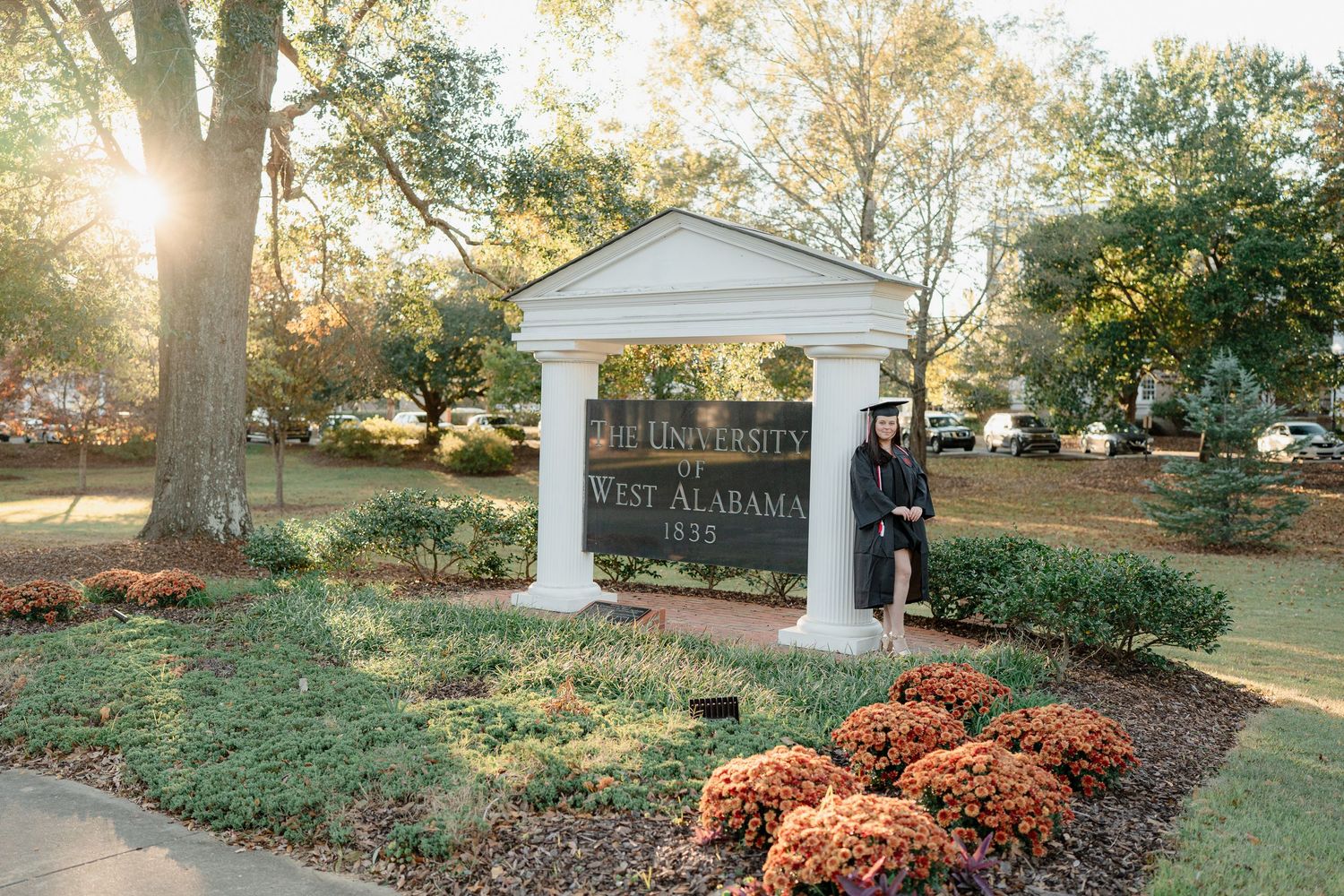 Sun-dappled autumn landscape with trees and pathways on college campus grounds.