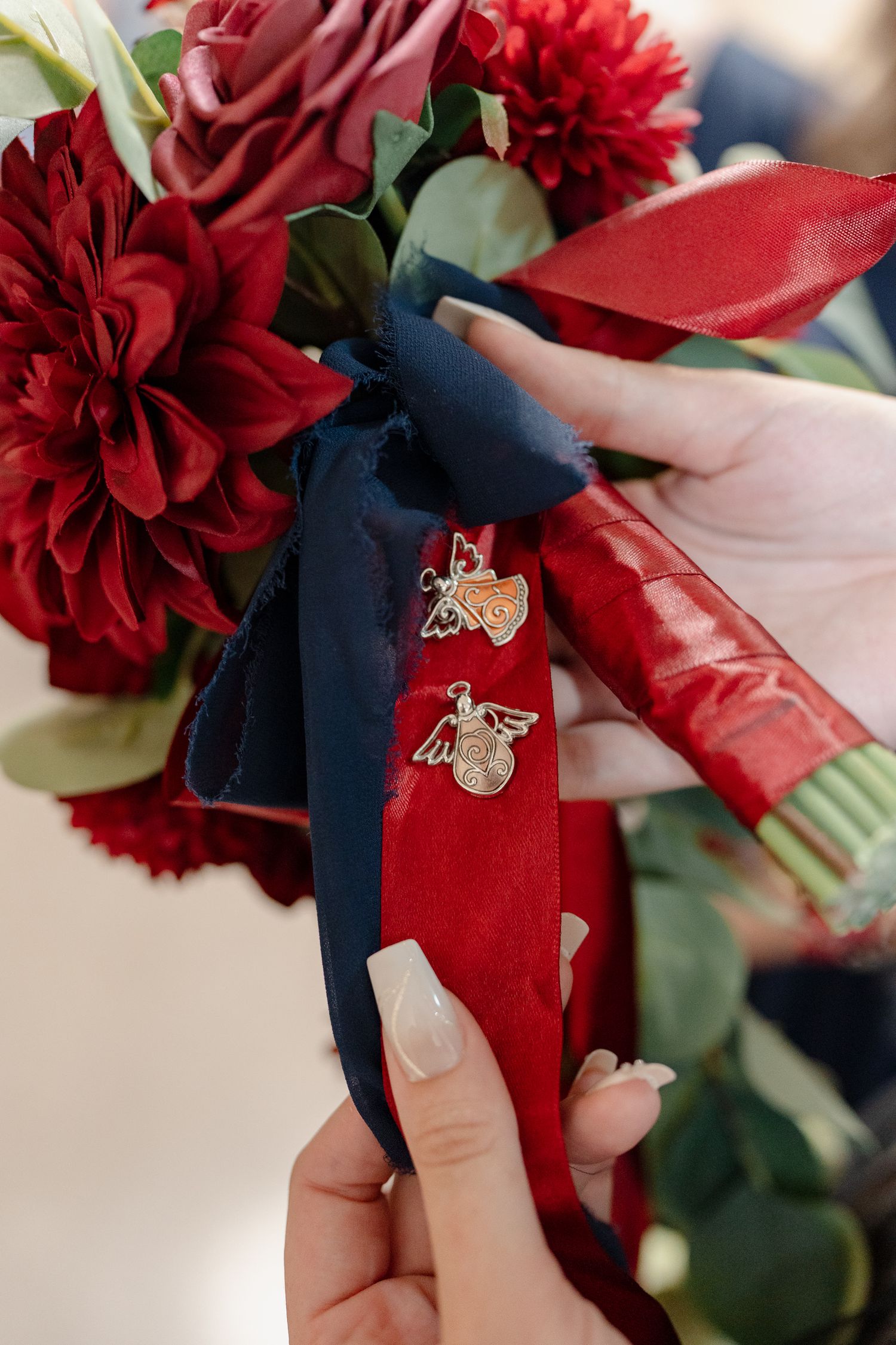 Red flowers with decorative butterfly pins attached to navy blue ribbons.