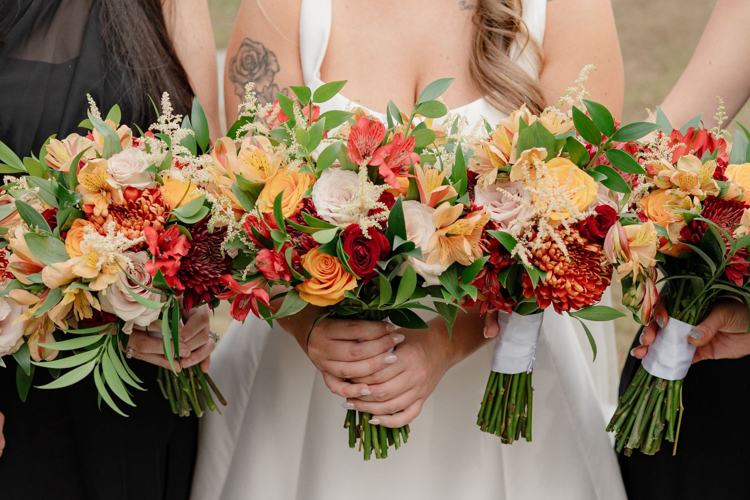 Wedding party bouquets lined up showing gradient of coral, peach and orange floral arrangements.