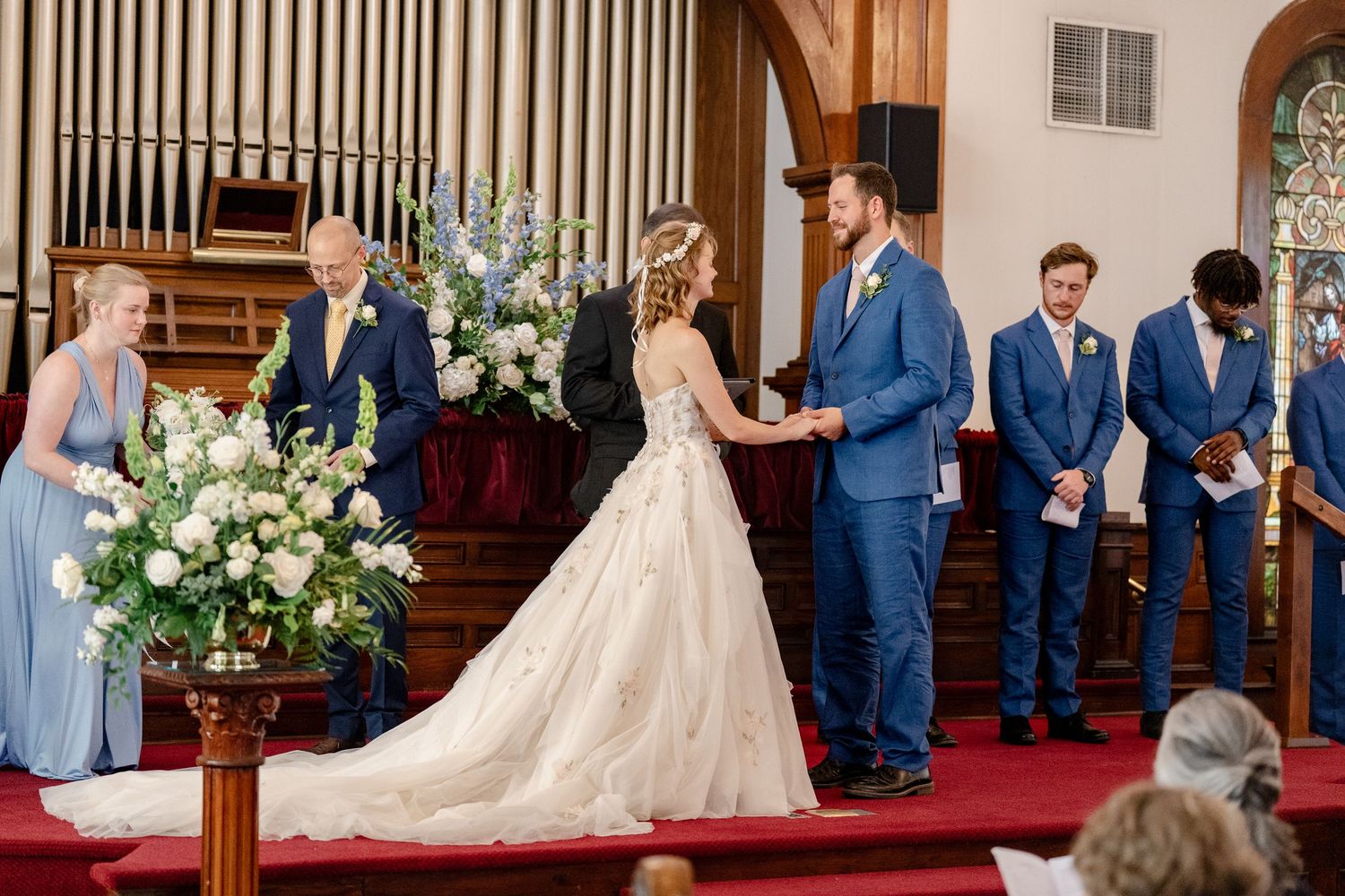 A traditional church wedding ceremony with stained glass windows and wooden pews filled with guests.