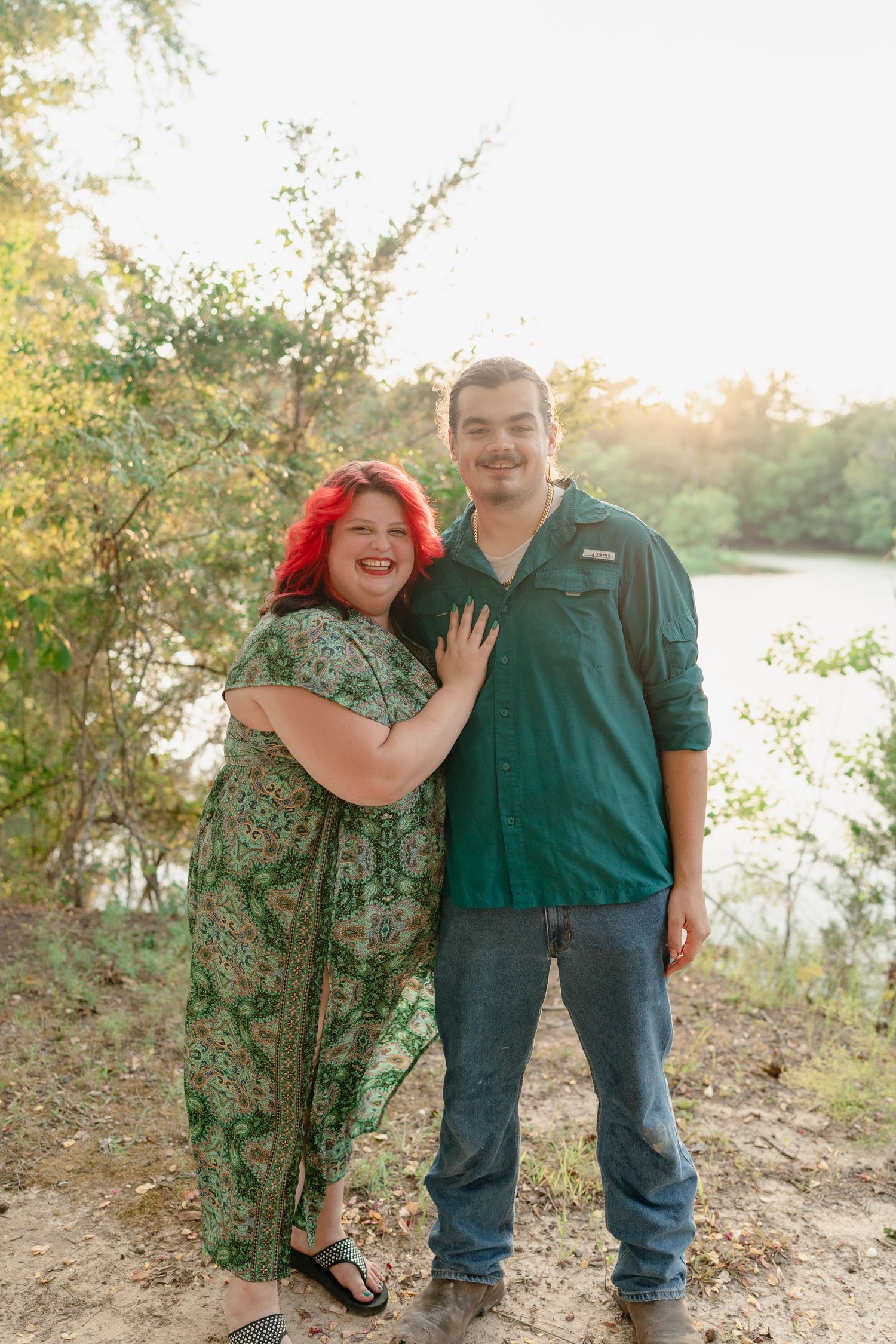 Couple shares intimate moments and laughter during a sunset photoshoot by the water.