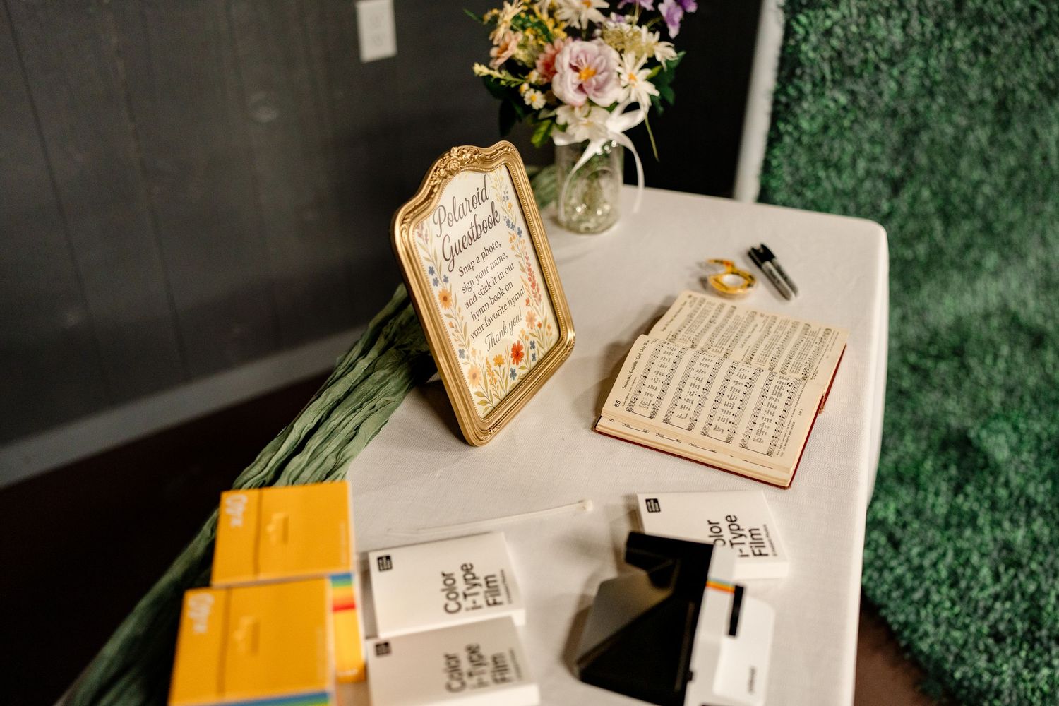 Wedding invitation suite with floral details, calligraphy, and decorative elements laid out on a green textured surface.