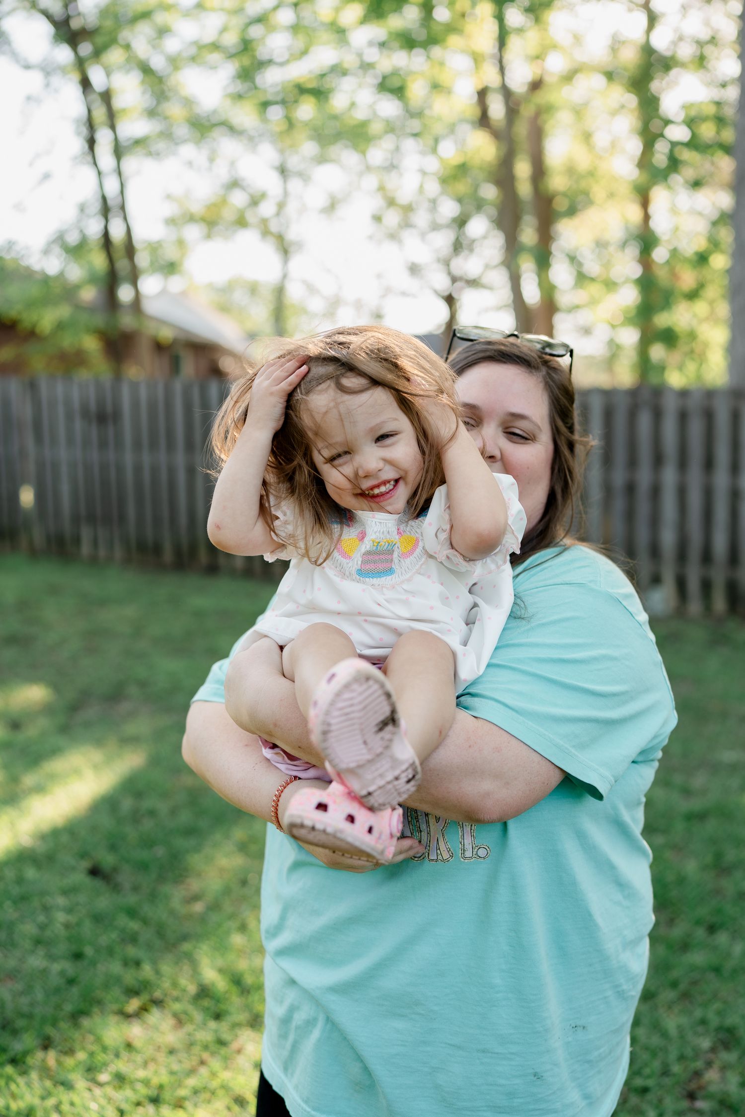 Joyful embrace between adult and child on sunny grass.