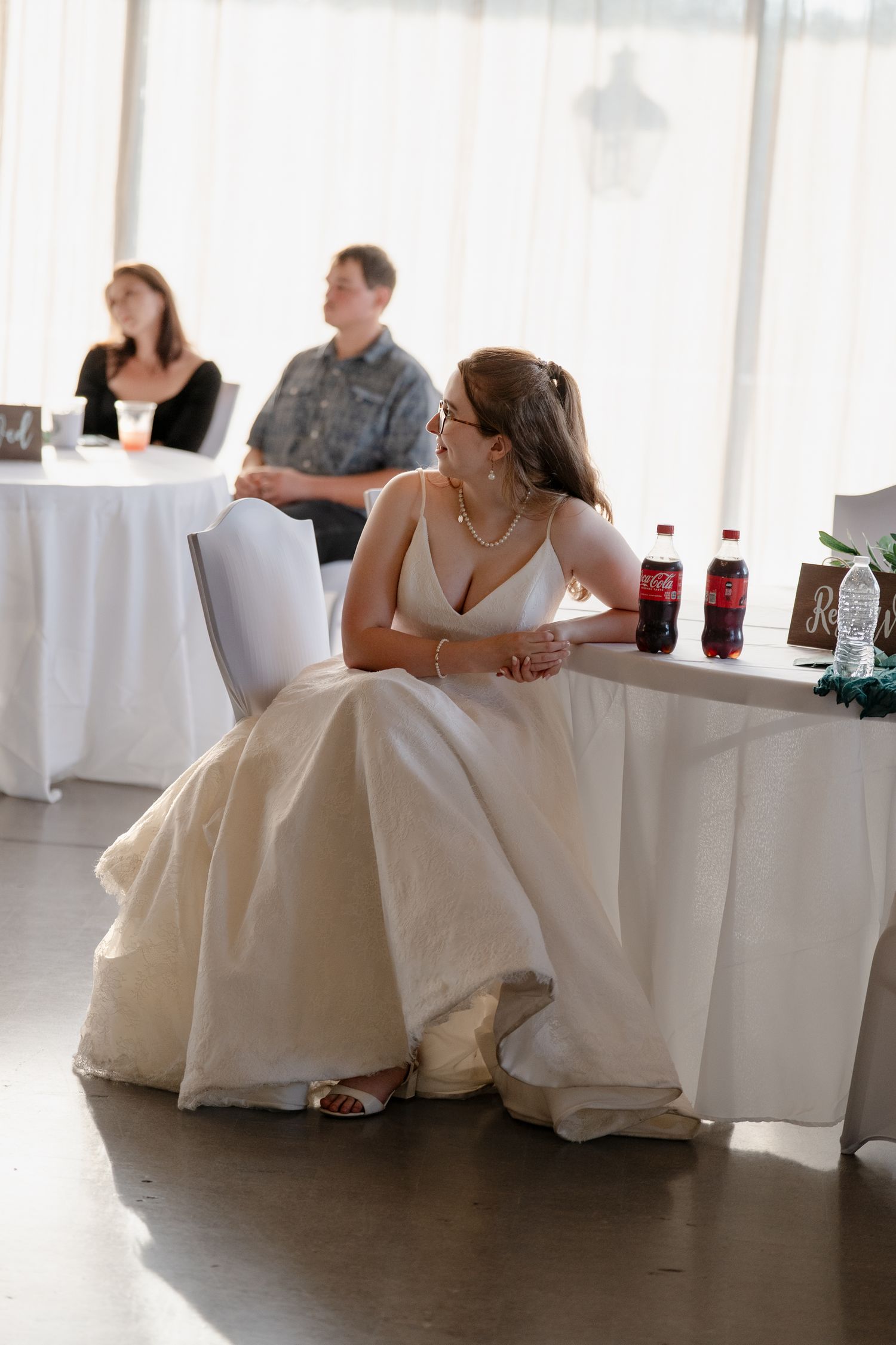 Wedding reception setup with elegant white table linens and decorative place settings.