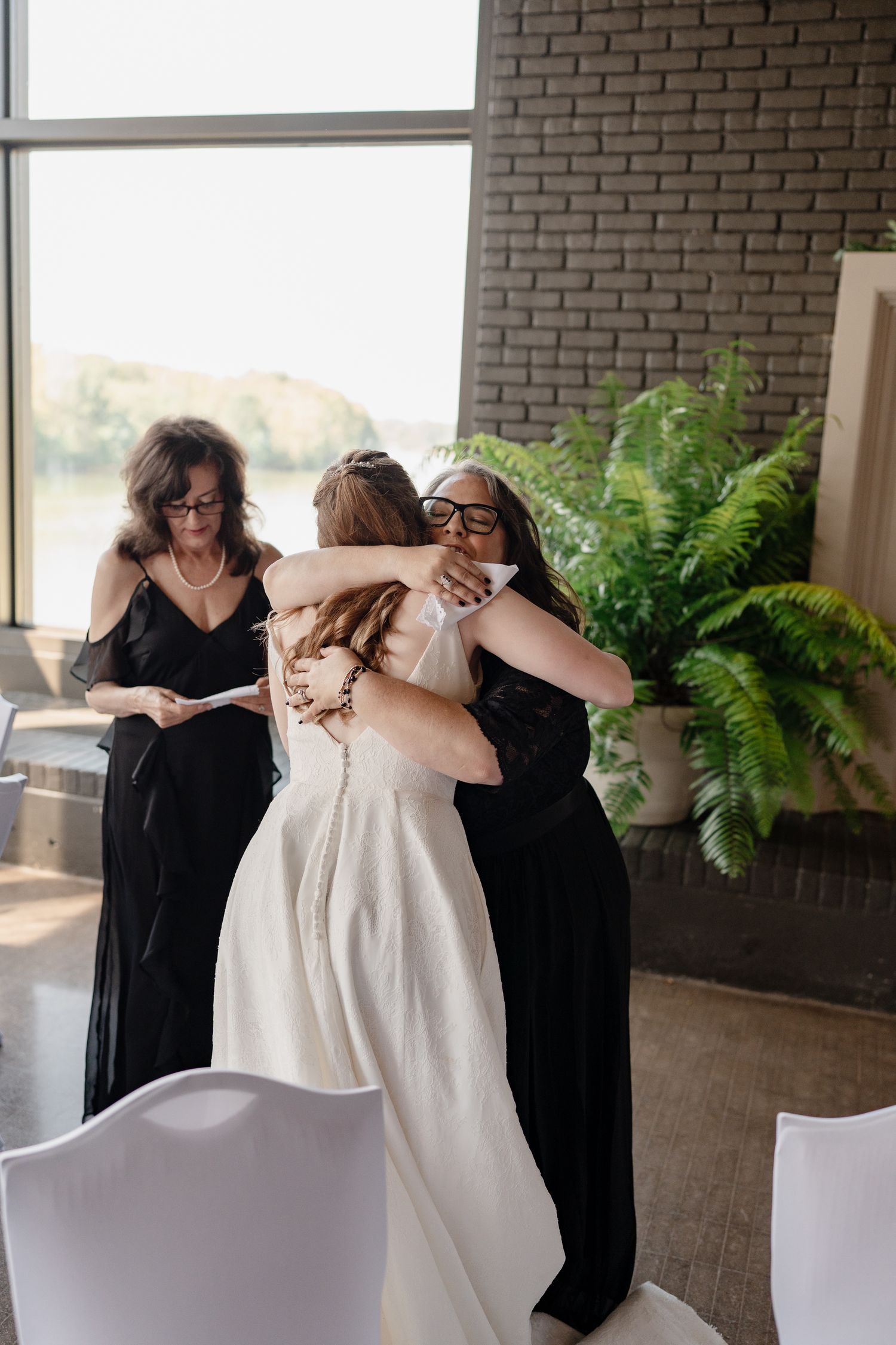 Wedding party members in black dresses helping with bridal preparations in an elegant venue.