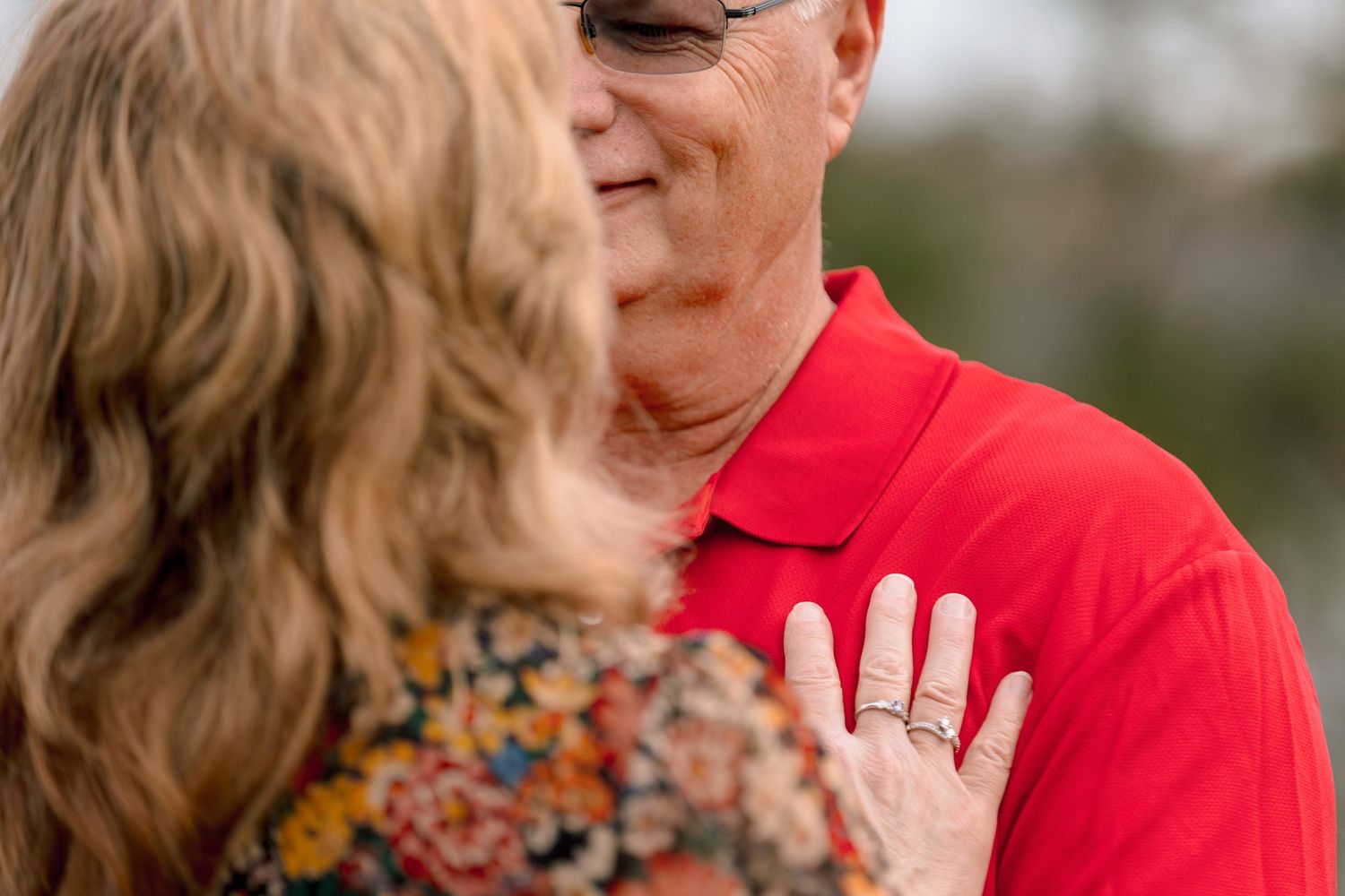 Close-up of a couple sharing a tender moment with a wedding ring visible on her hand.