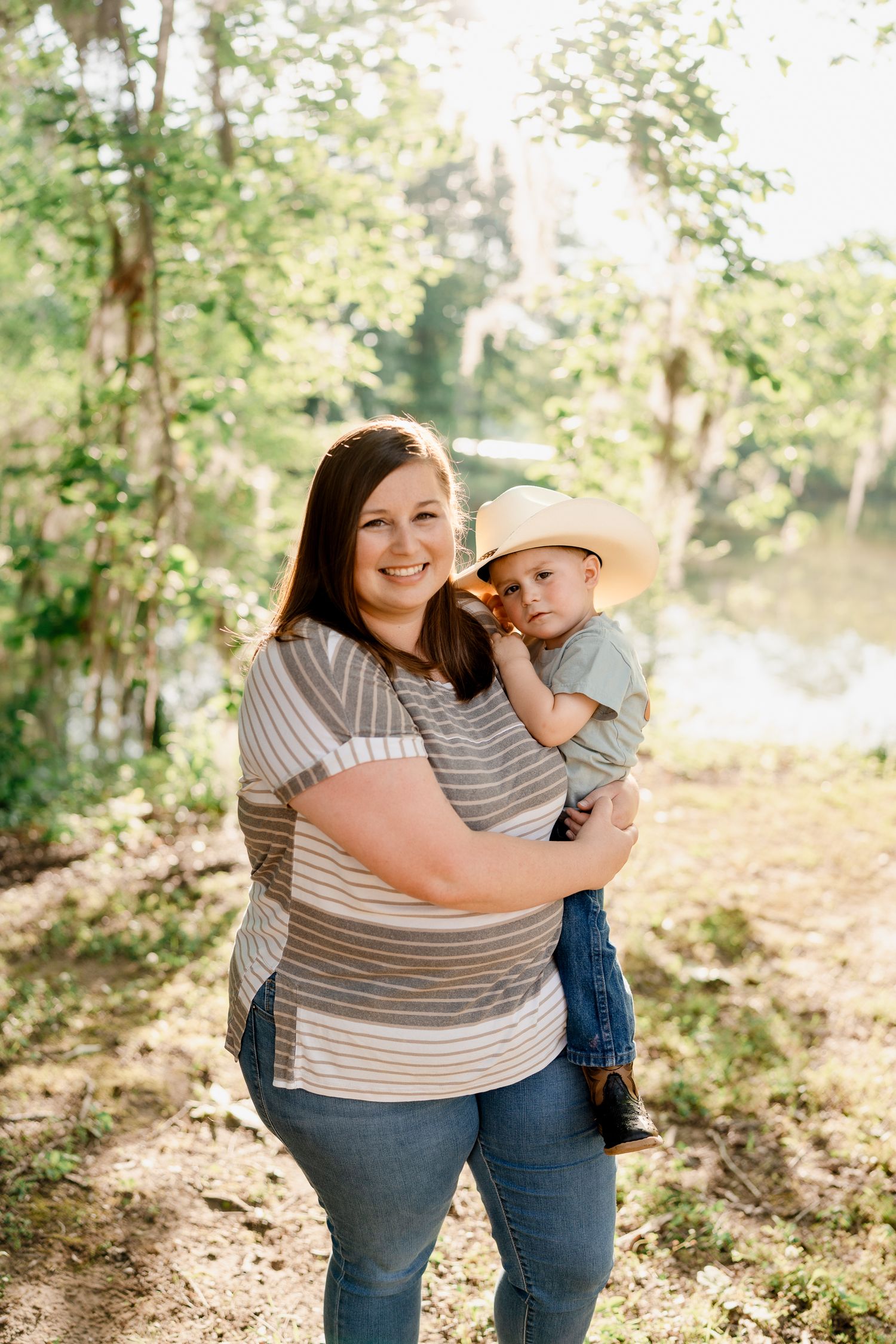Mother and child share tender moments during outdoor photo session in casual striped clothing.