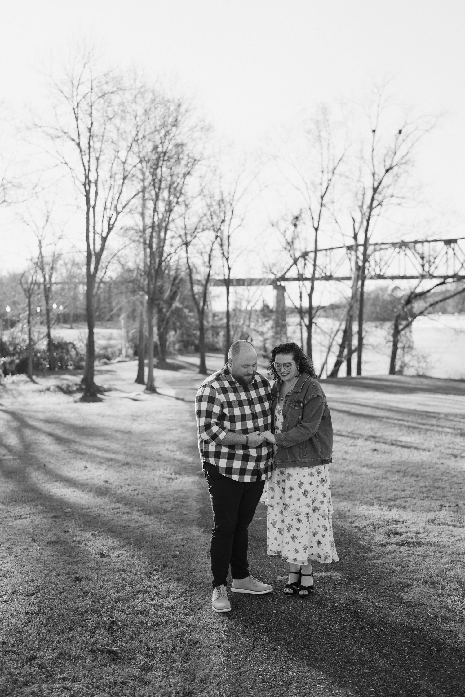 A black and white photo capturing a tender moment between two people in a park setting.