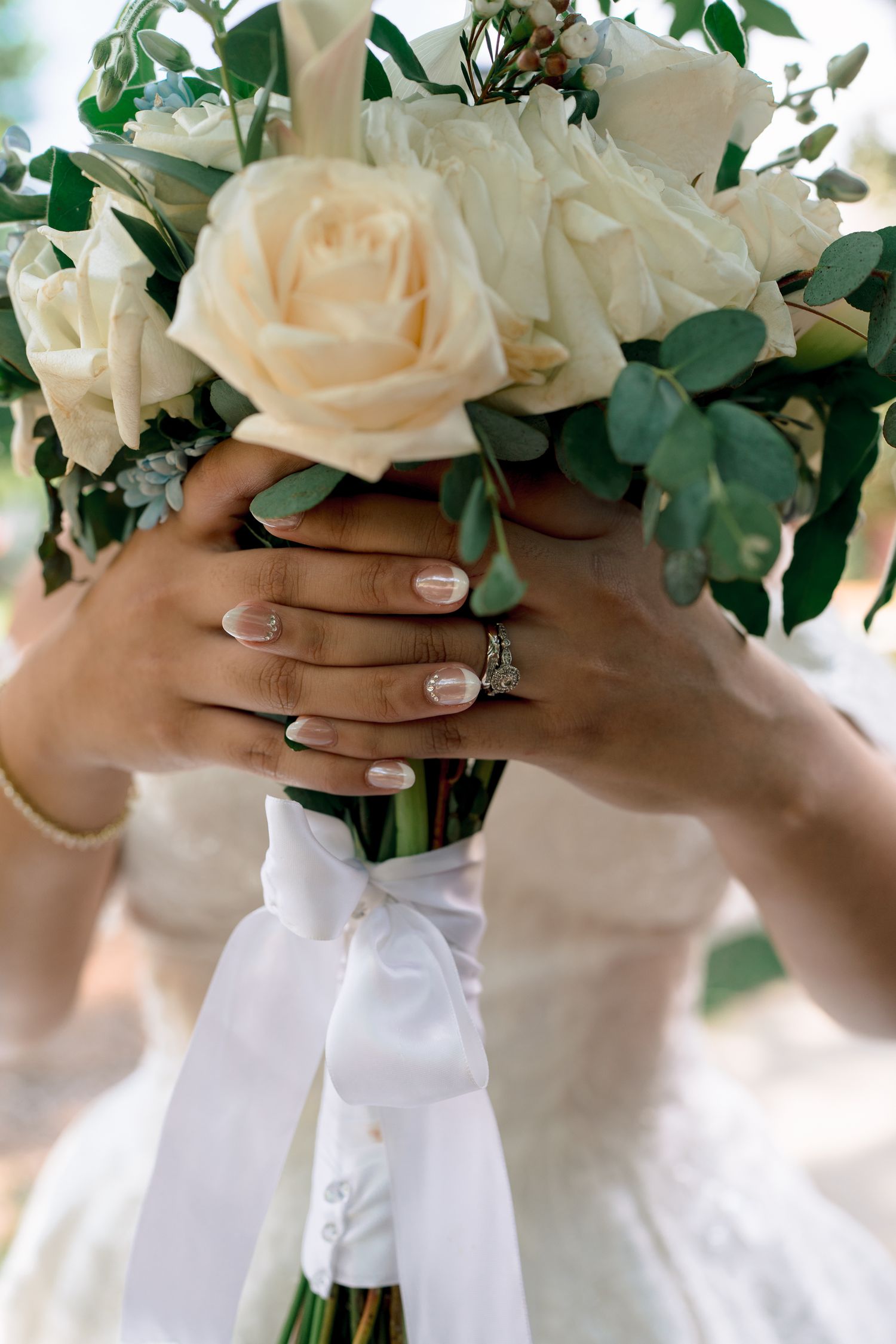 Delicate white and blush rose bouquets are held by hands wearing neutral manicures.
