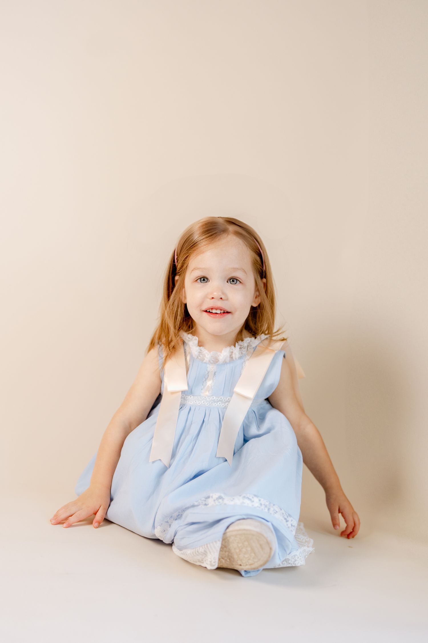 A light blue dress with white accents shimmers in soft studio lighting.