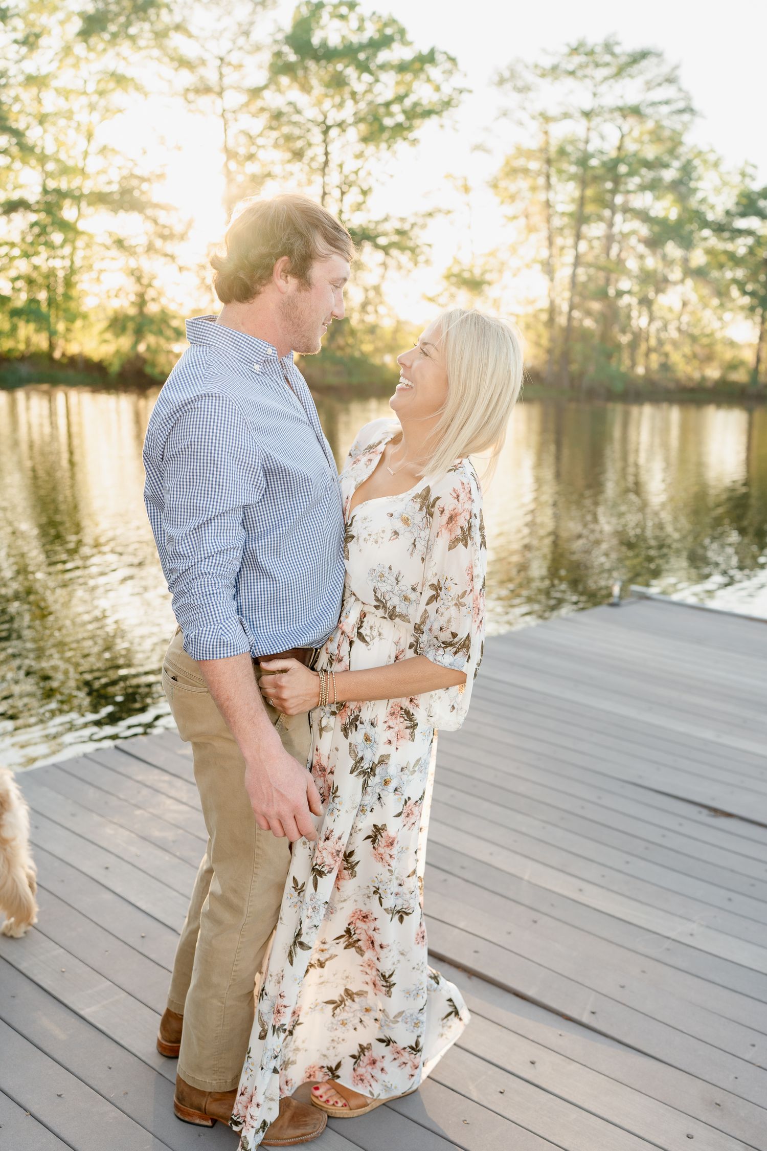 A couple in coordinated outfits shares a romantic moment on a dock by the lake.