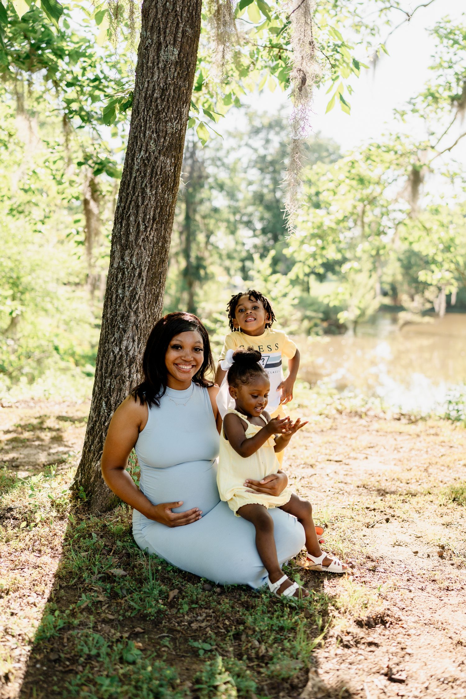 Mother and child relaxing together against tree trunk in forest setting.