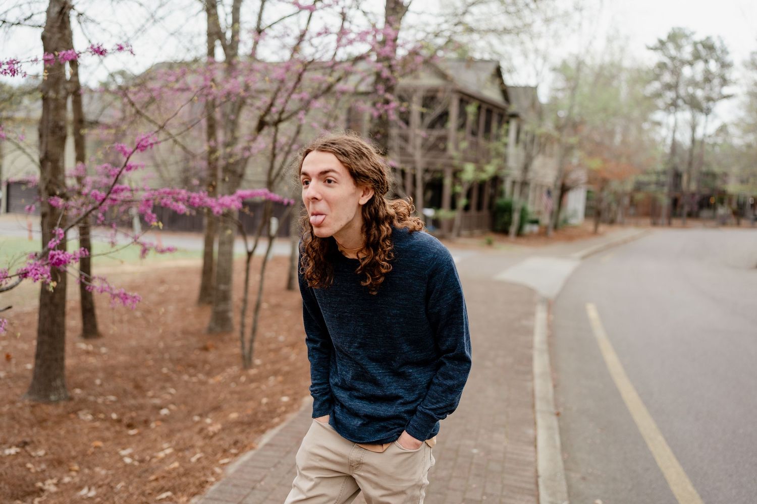 Person in dark sweater walking along scenic pathway with blooming spring trees.
