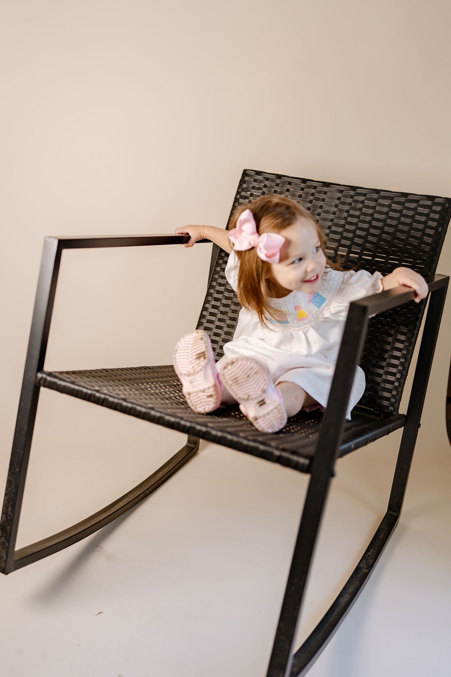 Child lounges on sleek black modern chair against white background.