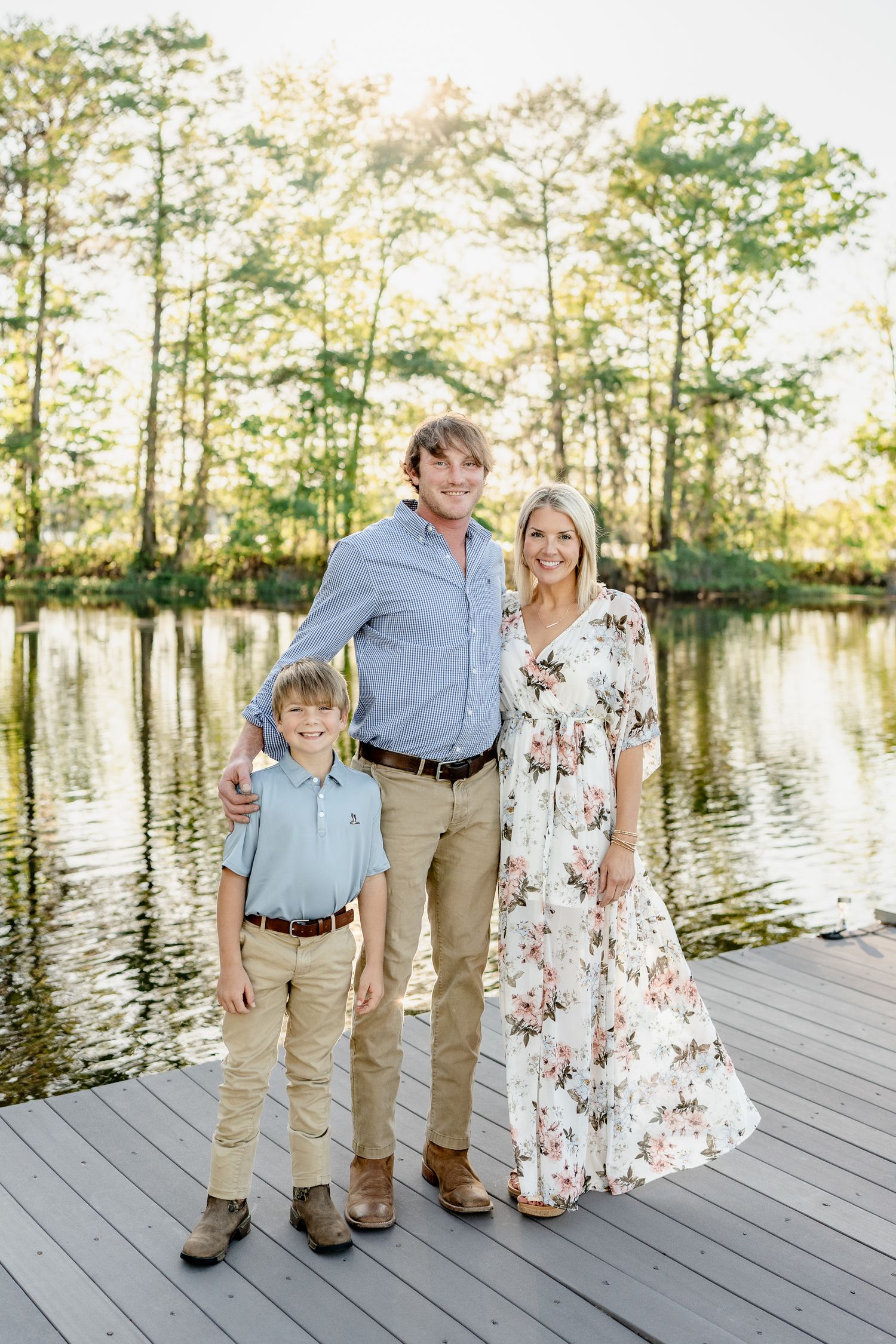 Family photos taken on a wooden dock overlooking a serene lake surrounded by trees.